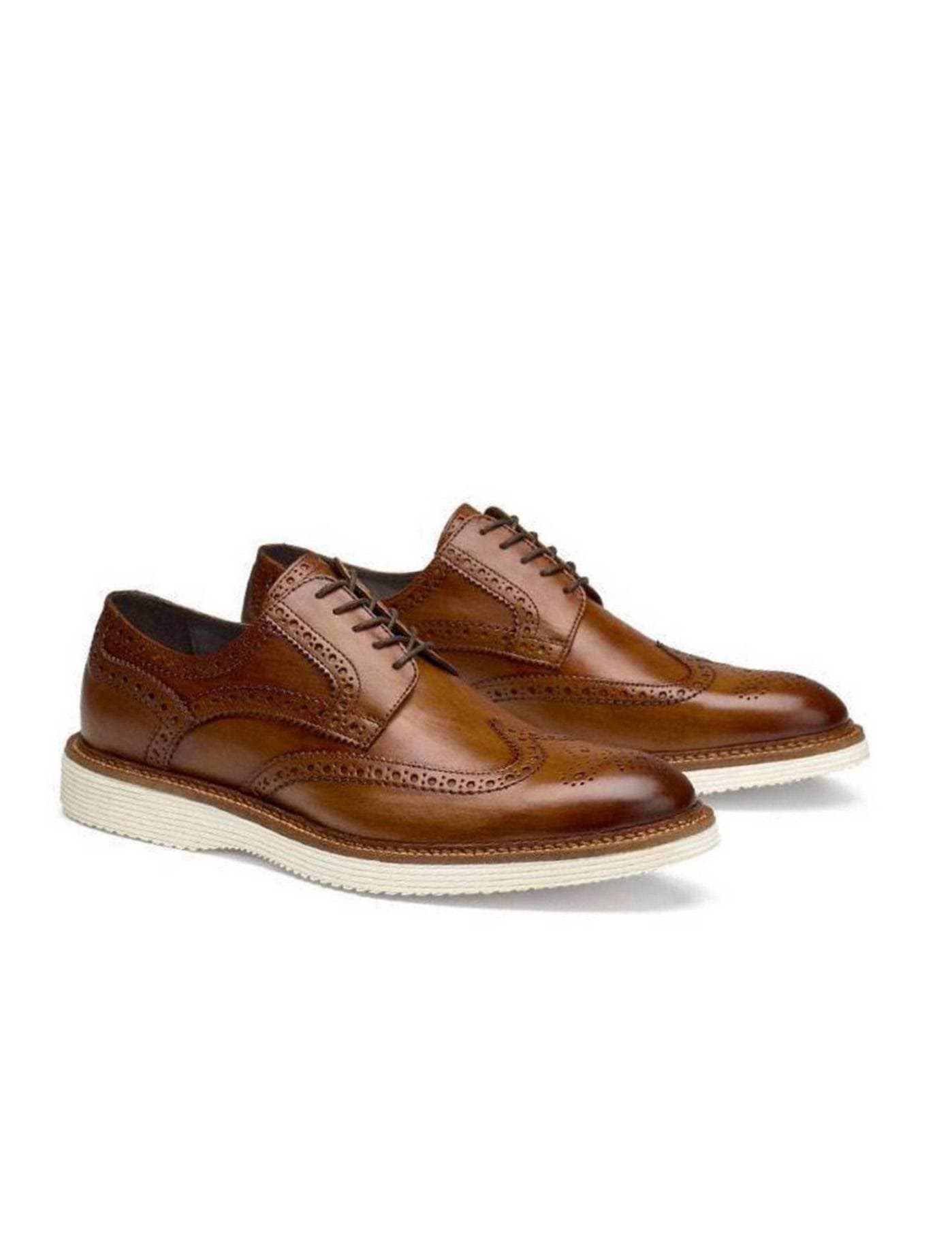 Brown leather wingtip shoes with white soles on a white background.