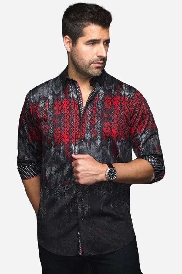 A man wearing a black and red dress shirt with an intricate patterned design. The shirt has rolled-up sleeves, with contrasting inner cuff details, adding a bold and modern style to his look.
