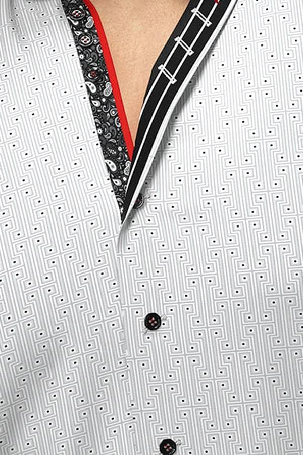 A man wearing a cotton knit geometric dress shirt with a subtle, textured pattern. The shirt has contrasting inner collar and cuff details in black and red, adding a sophisticated touch. The sleeves are rolled up, and the man poses with a confident expression.