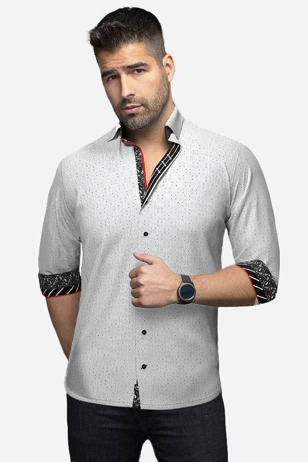A man wearing a cotton knit geometric dress shirt with a subtle, textured pattern. The shirt has contrasting inner collar and cuff details in black and red, adding a sophisticated touch. The sleeves are rolled up, and the man poses with a confident expression.