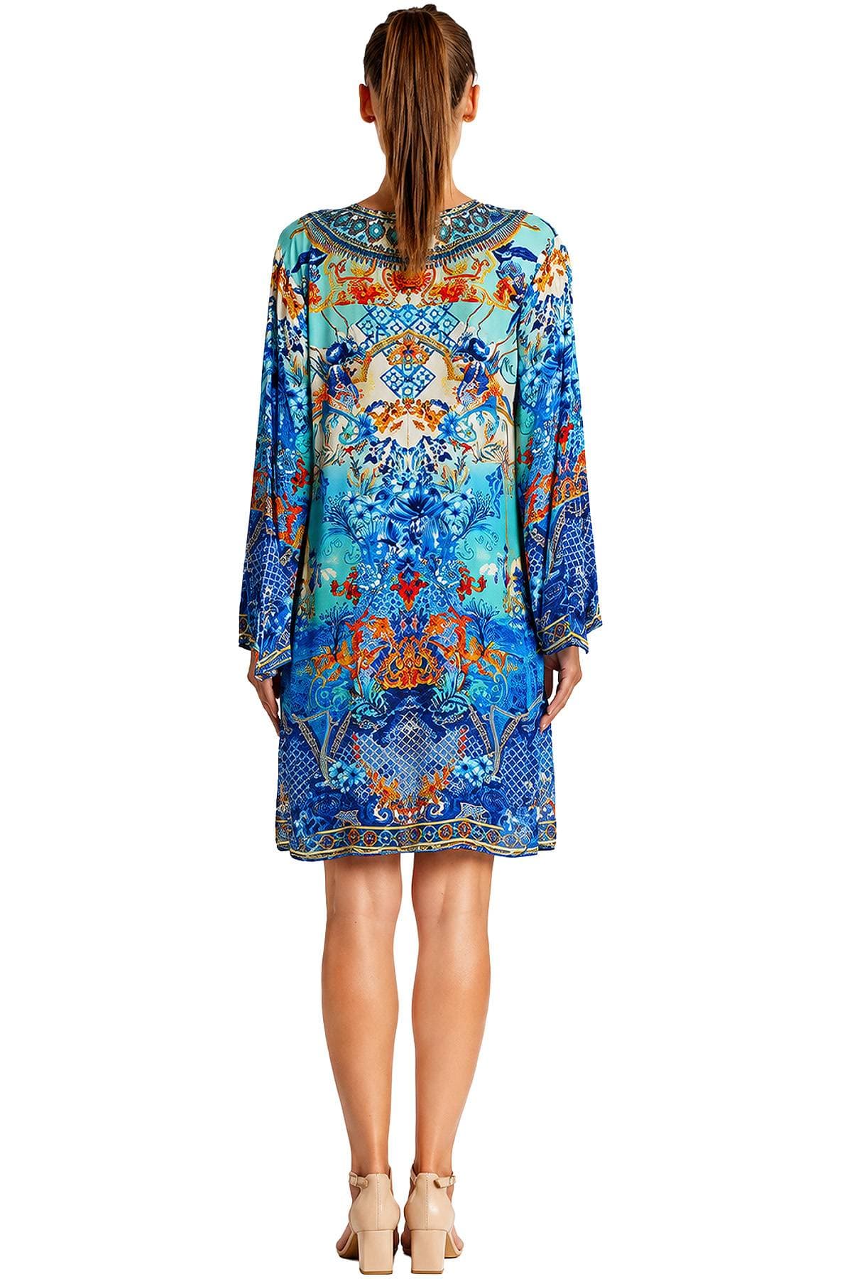 A person wearing a colorful, patterned dress with long sleeves and beige heeled sandals is shown from the back.