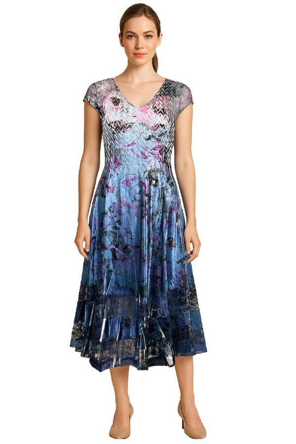 Front view of a model wearing a blue and purple floral satin midi dress with cap sleeves and a V-neckline. The dress has a fitted waist, flared skirt, and dark lace trim at the hem, paired with nude heels.