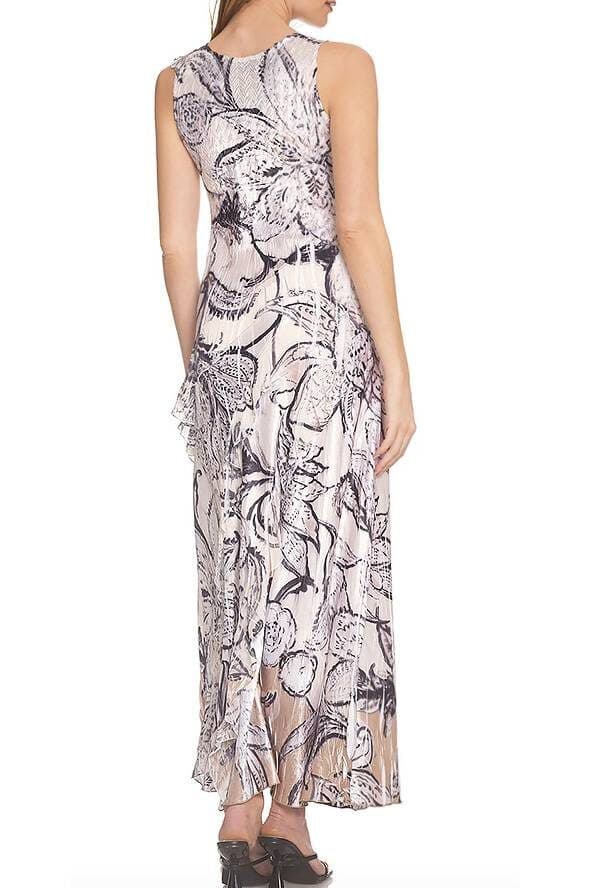 Back view of a model wearing a sleeveless maxi dress with a black and white floral print on a cream background. The dress has a fitted bodice, flowing skirt, and beige-toned hem, paired with black heels.