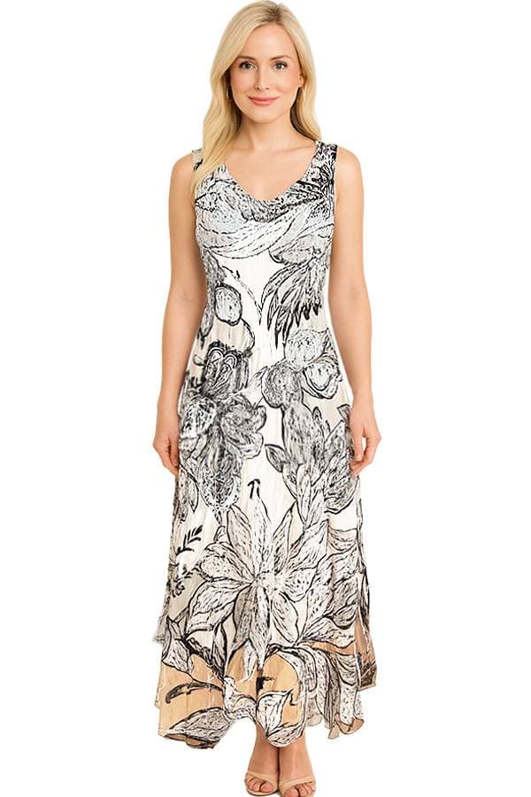 Front view of a model wearing a sleeveless maxi dress with a black and white floral print on a cream background. The dress has a V-neckline, a flowing A-line skirt, and a soft beige tone at the hem, paired with nude sandals.