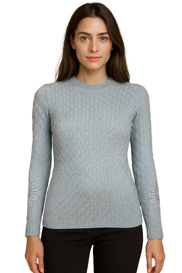 Woman wearing a light gray textured sweater with long sleeves, wavy knit pattern, and raised floral knit detail on the sleeves.