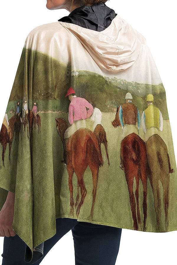 A person wears a poncho with a printed image of jockeys riding horses.