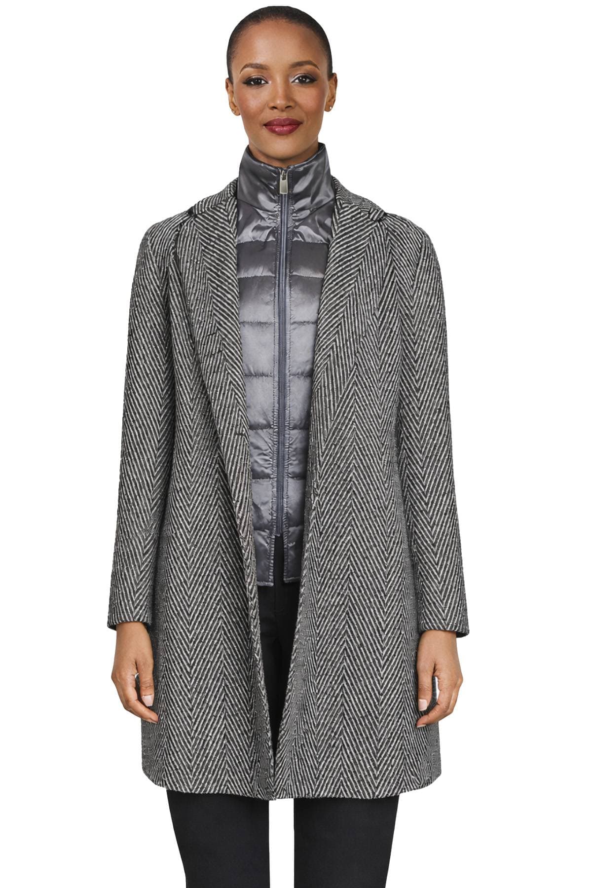 A person wearing a gray herringbone coat over a shiny gray zip-up jacket.
