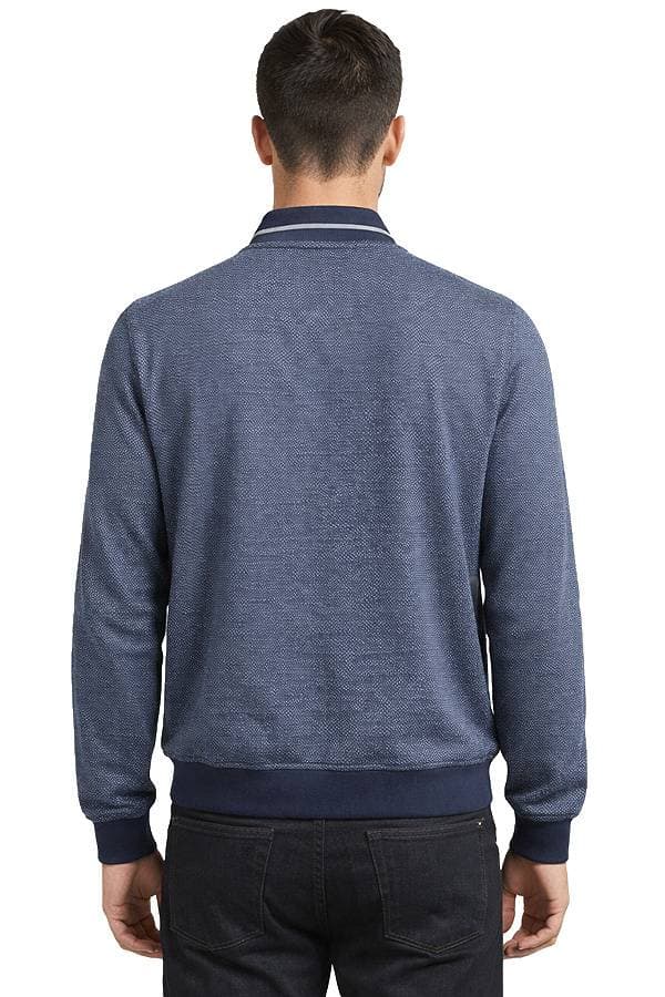 A person wearing a blue textured sweater and black jeans is shown from behind.