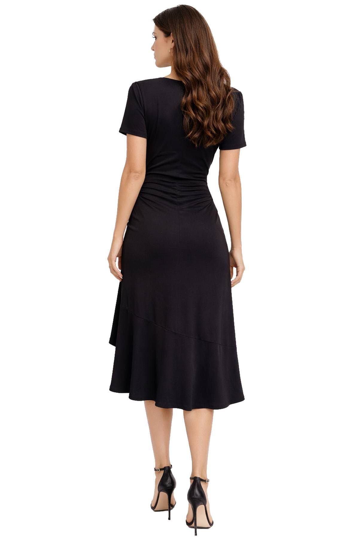 A woman in a black dress and high heels is standing with her back to the camera.