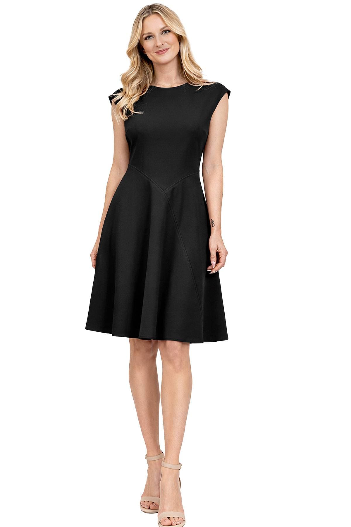 A woman is wearing a sleeveless black dress and beige high-heeled sandals.