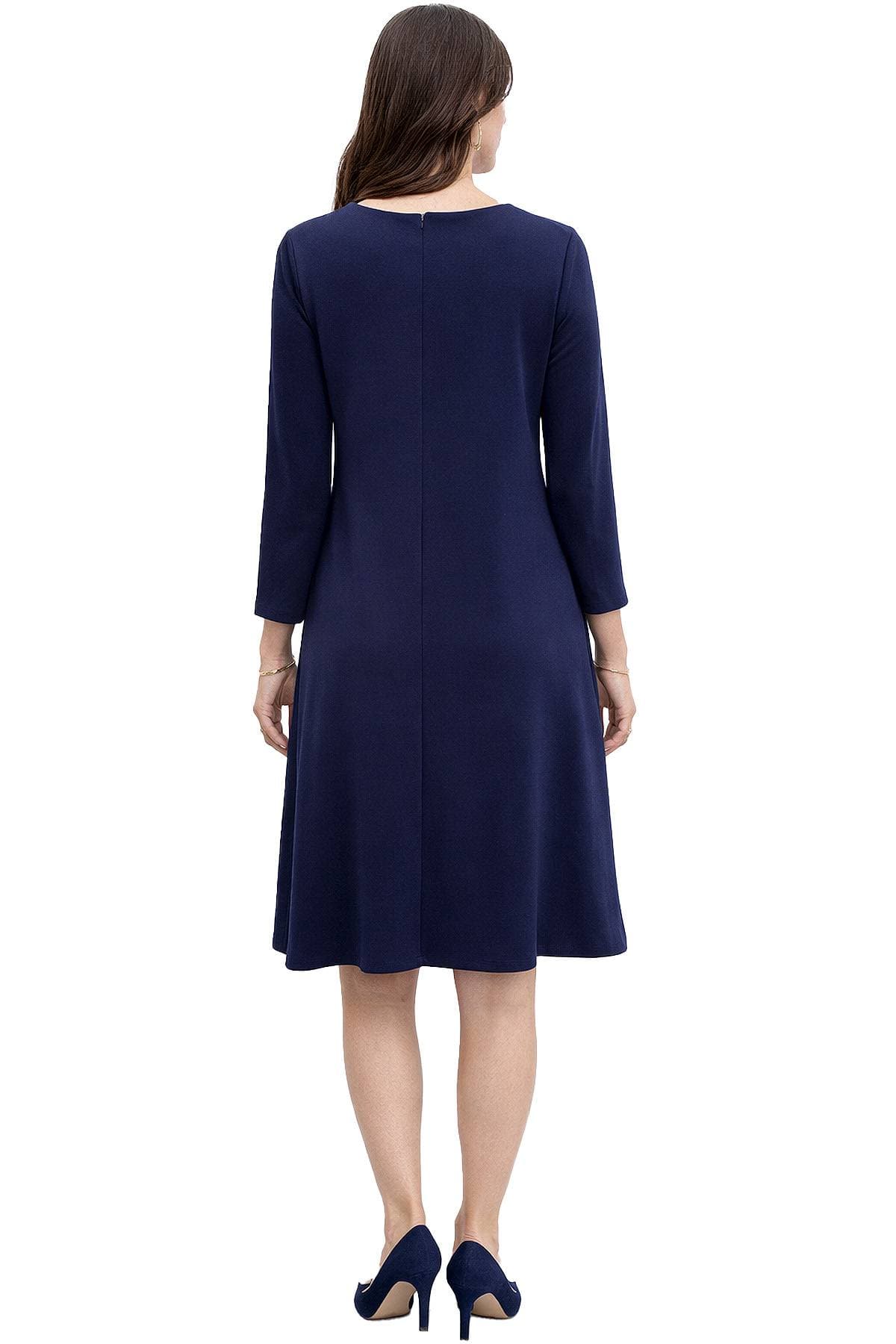 A woman is wearing a navy blue long-sleeve dress and matching heels, viewed from behind.