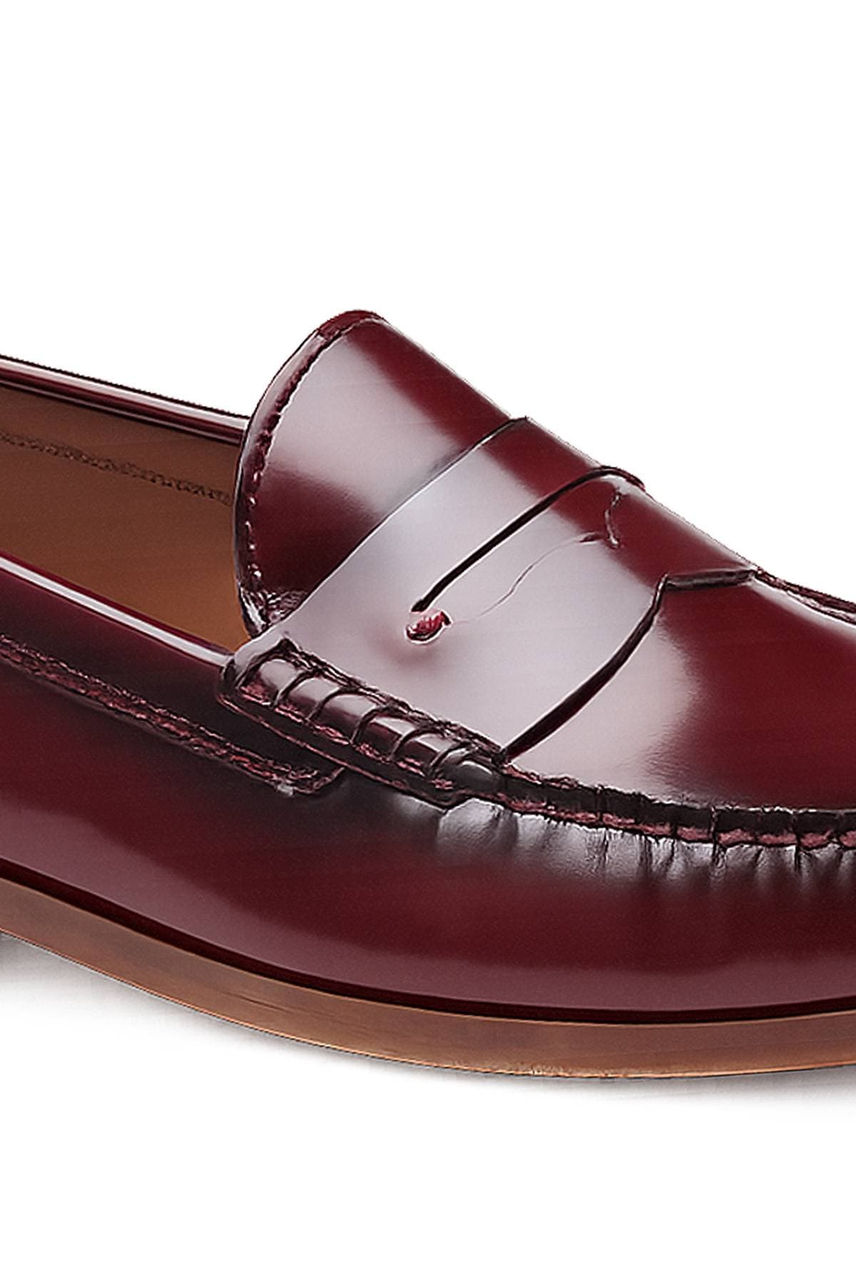 A close-up view of a shiny burgundy leather penny loafer shoe.