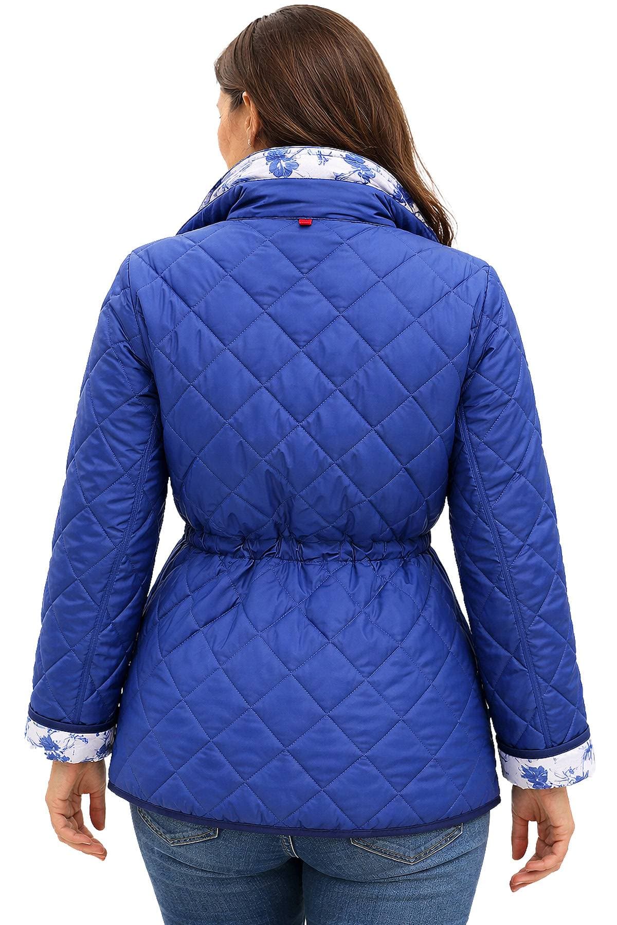 A person wearing a blue quilted jacket with floral-patterned cuffs and collar from the back.