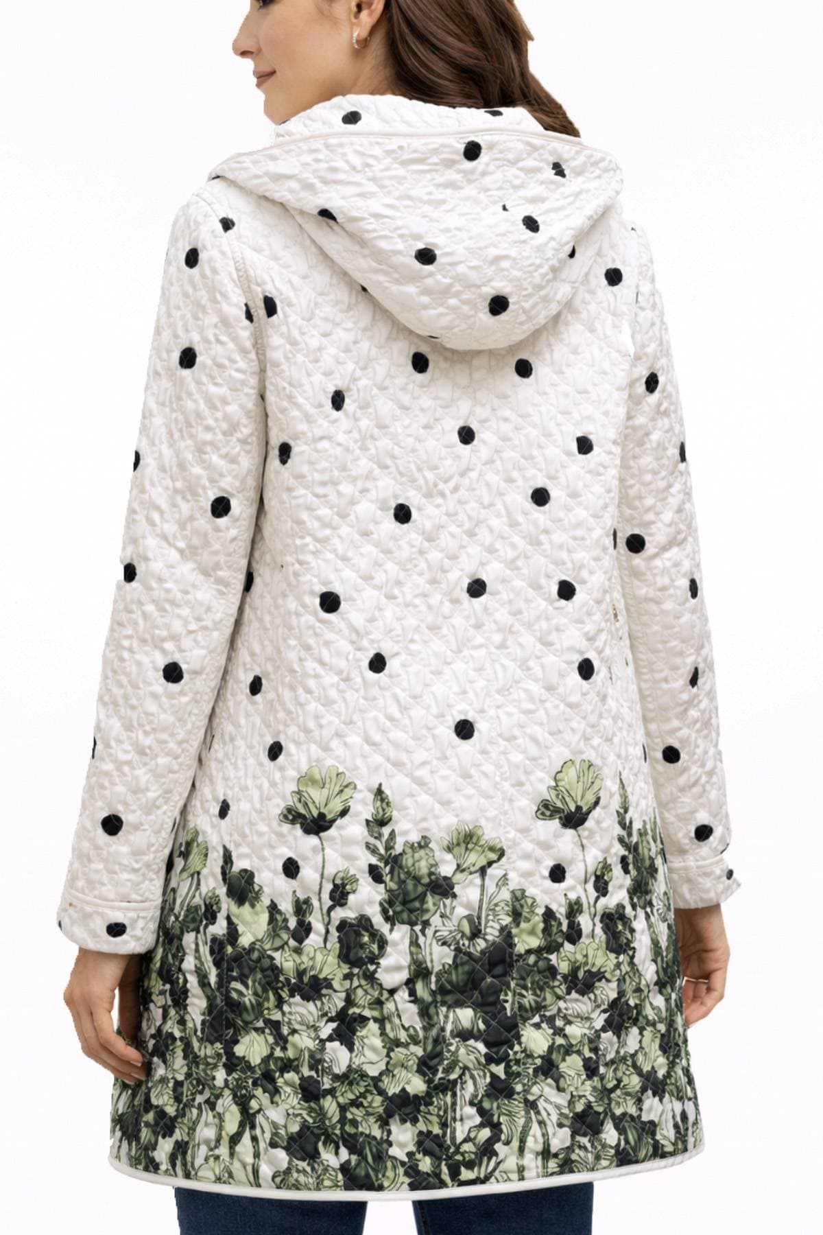 A woman models a white quilted coat with black polka dots and a floral pattern at the hem.