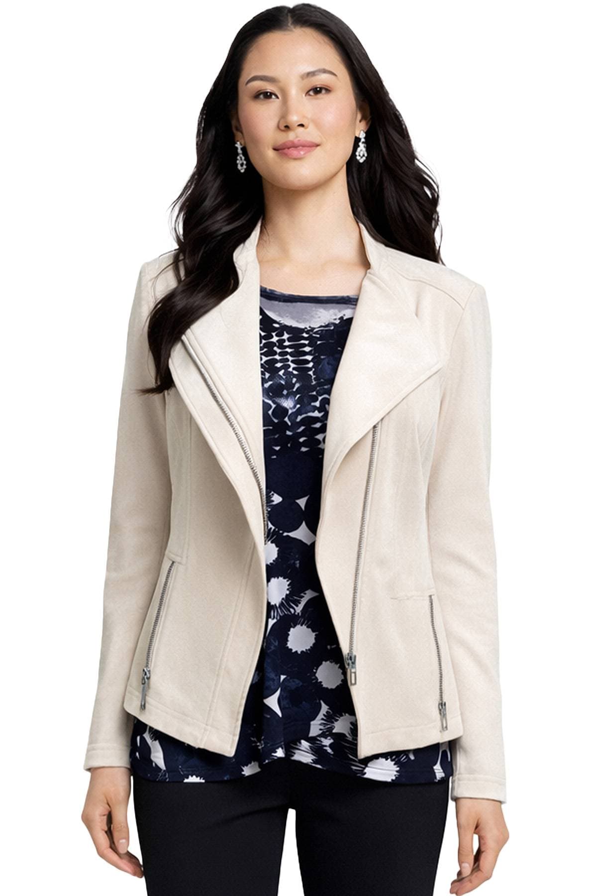 A woman wearing a light beige jacket over a patterned navy blue top with earrings.