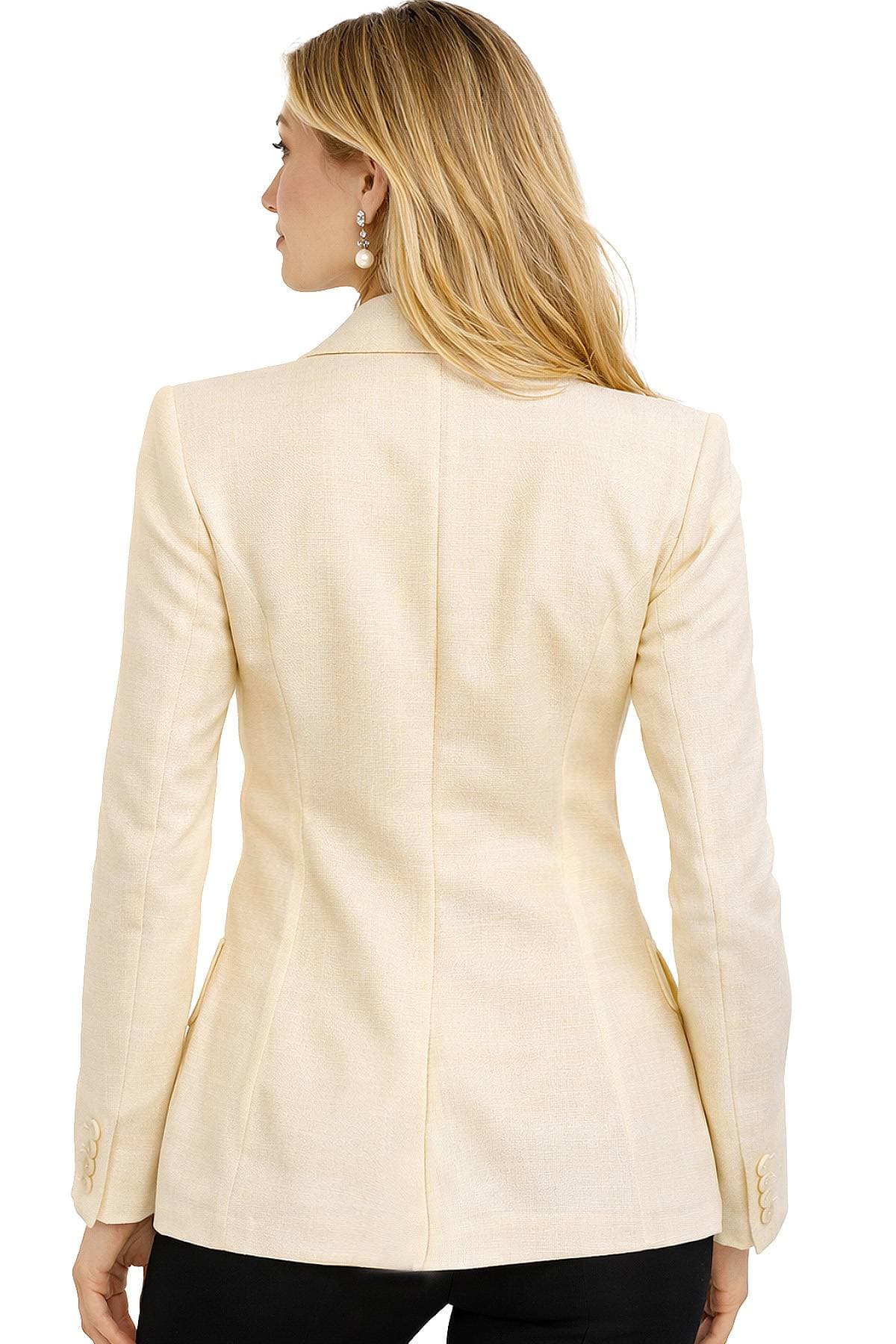 A woman with long blond hair is wearing a light beige blazer and facing away from the camera.