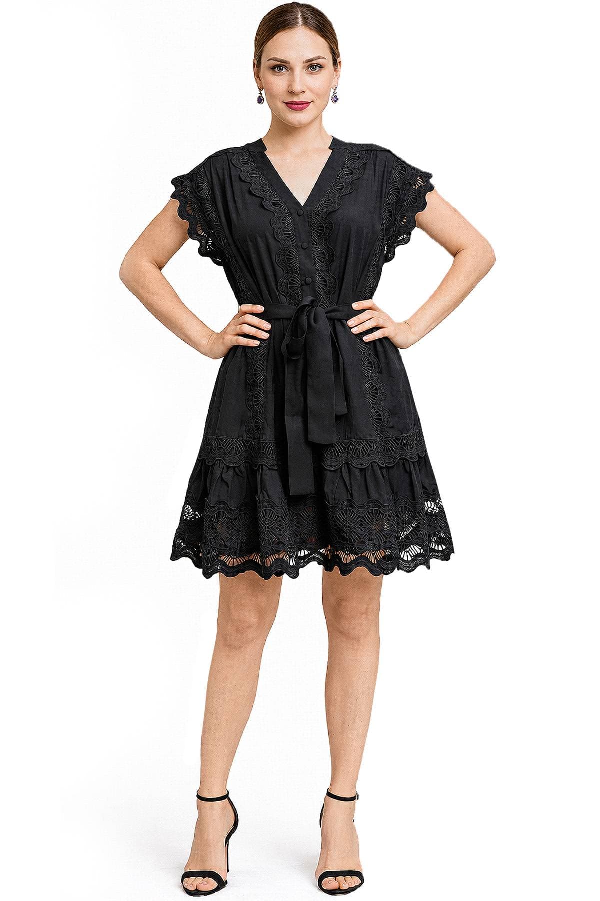 A woman wearing a black lace-trimmed dress with a tied waist and sandals.