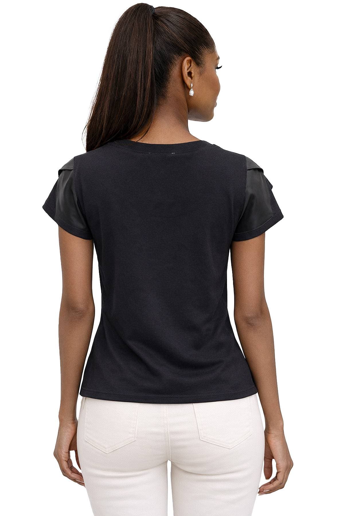 A woman with long hair in a ponytail is wearing a black short-sleeved top with leather accents on the sleeves and white pants, viewed from the back.