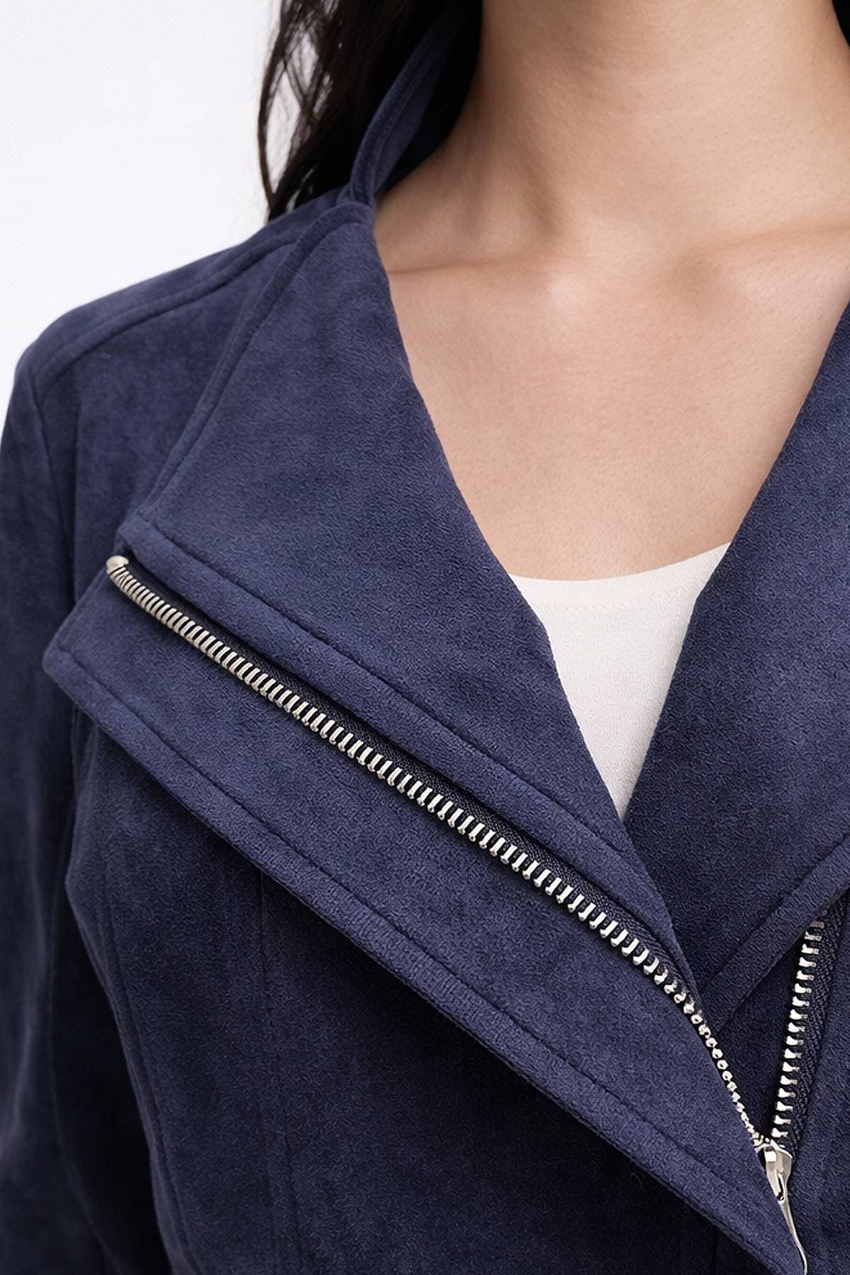 A person wearing a navy blue suede jacket with a zipper detail.