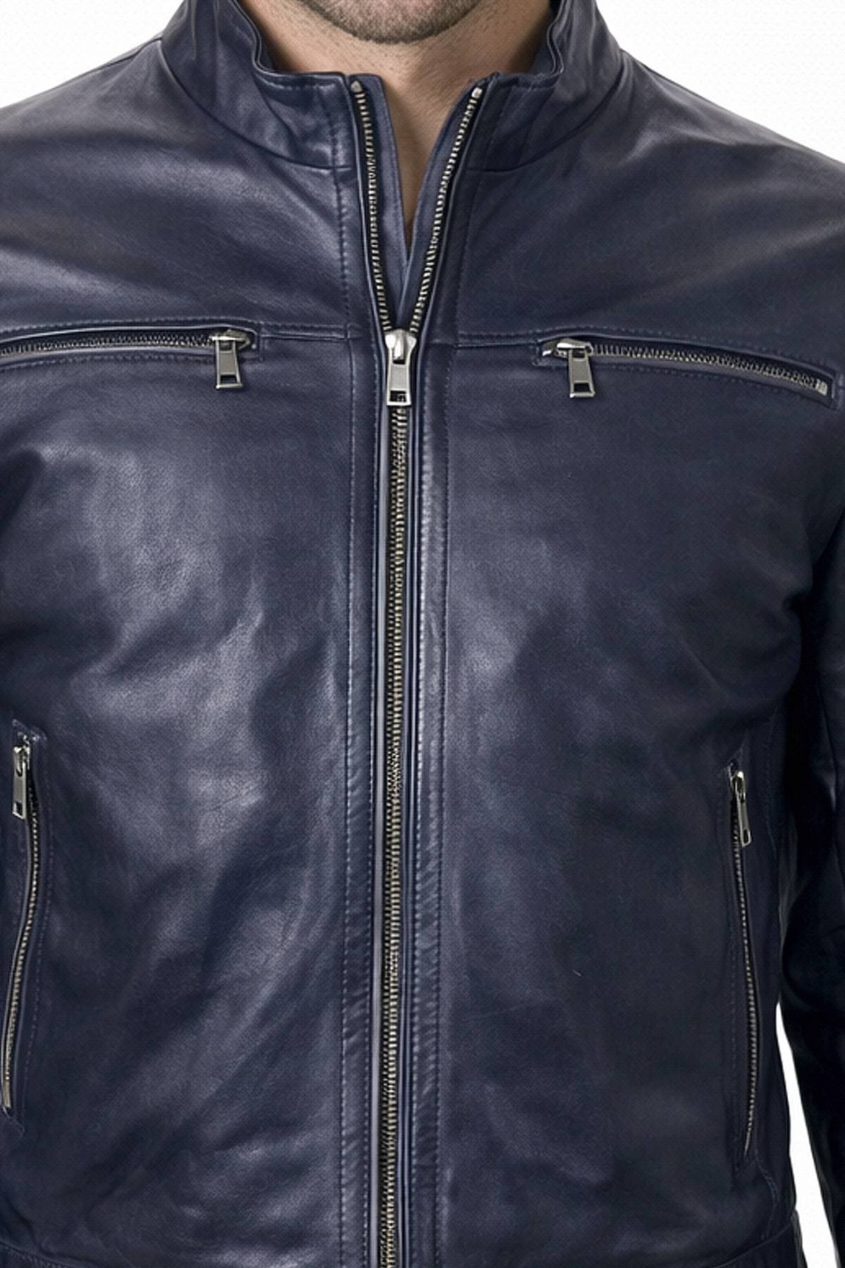 A man wearing a dark blue leather jacket with front and chest zippers.