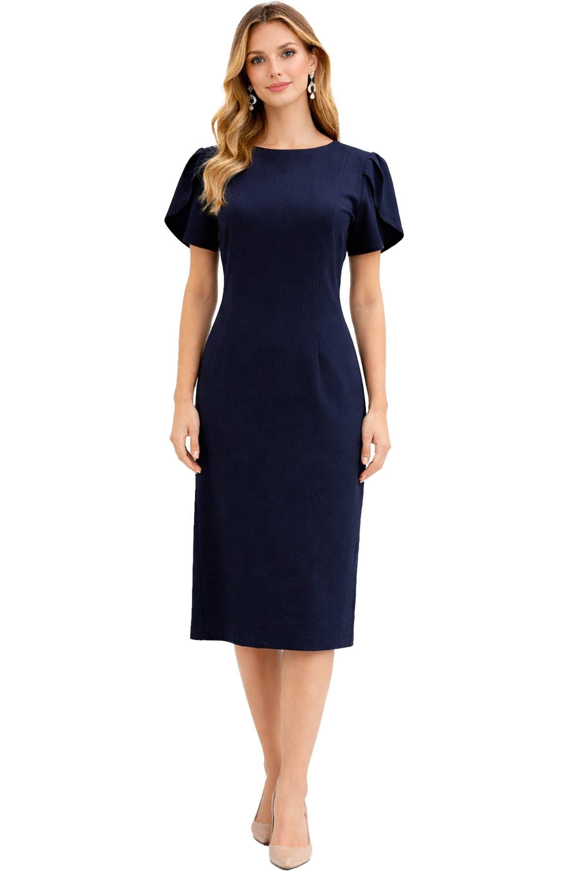 A woman is wearing a navy knee-length dress with short, puffed sleeves and nude heels.