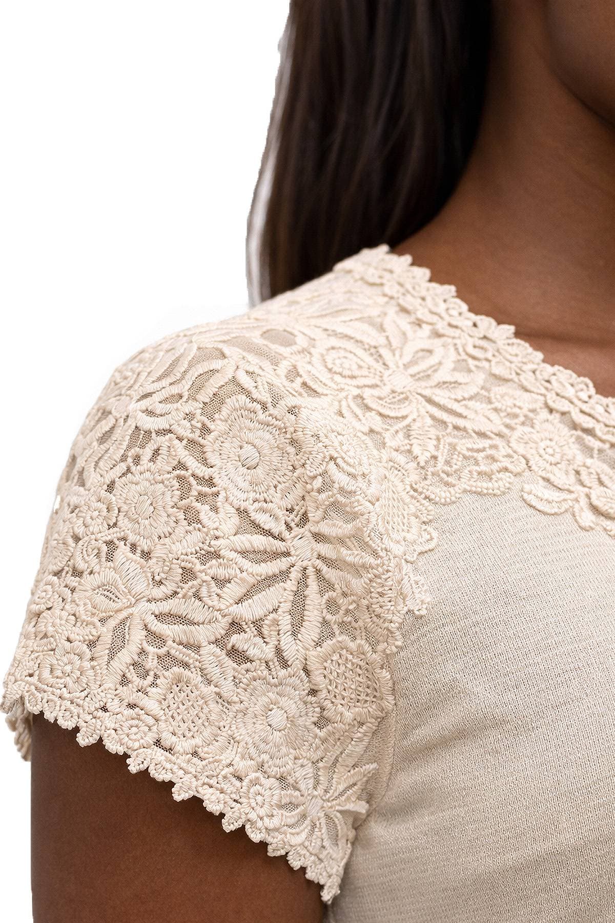 A close-up of a person wearing a beige top with intricate lace detailing on the shoulder and sleeve.