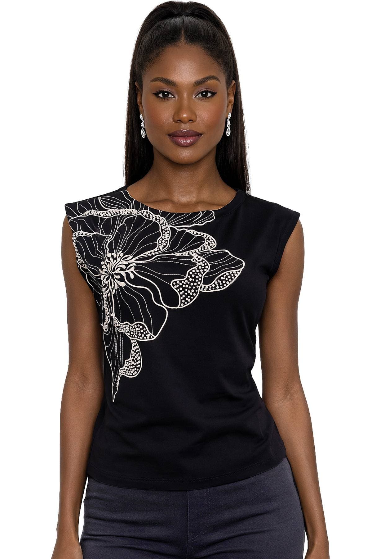 A woman wearing a sleeveless black top with a large white floral design on the shoulder.