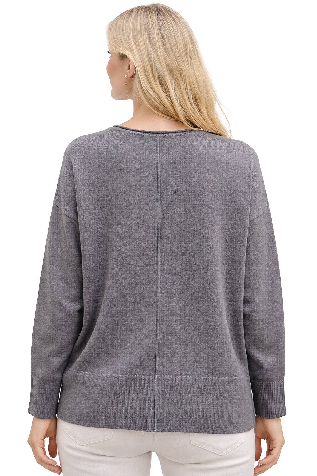 A person with long blond hair wearing a gray sweater viewed from the back.