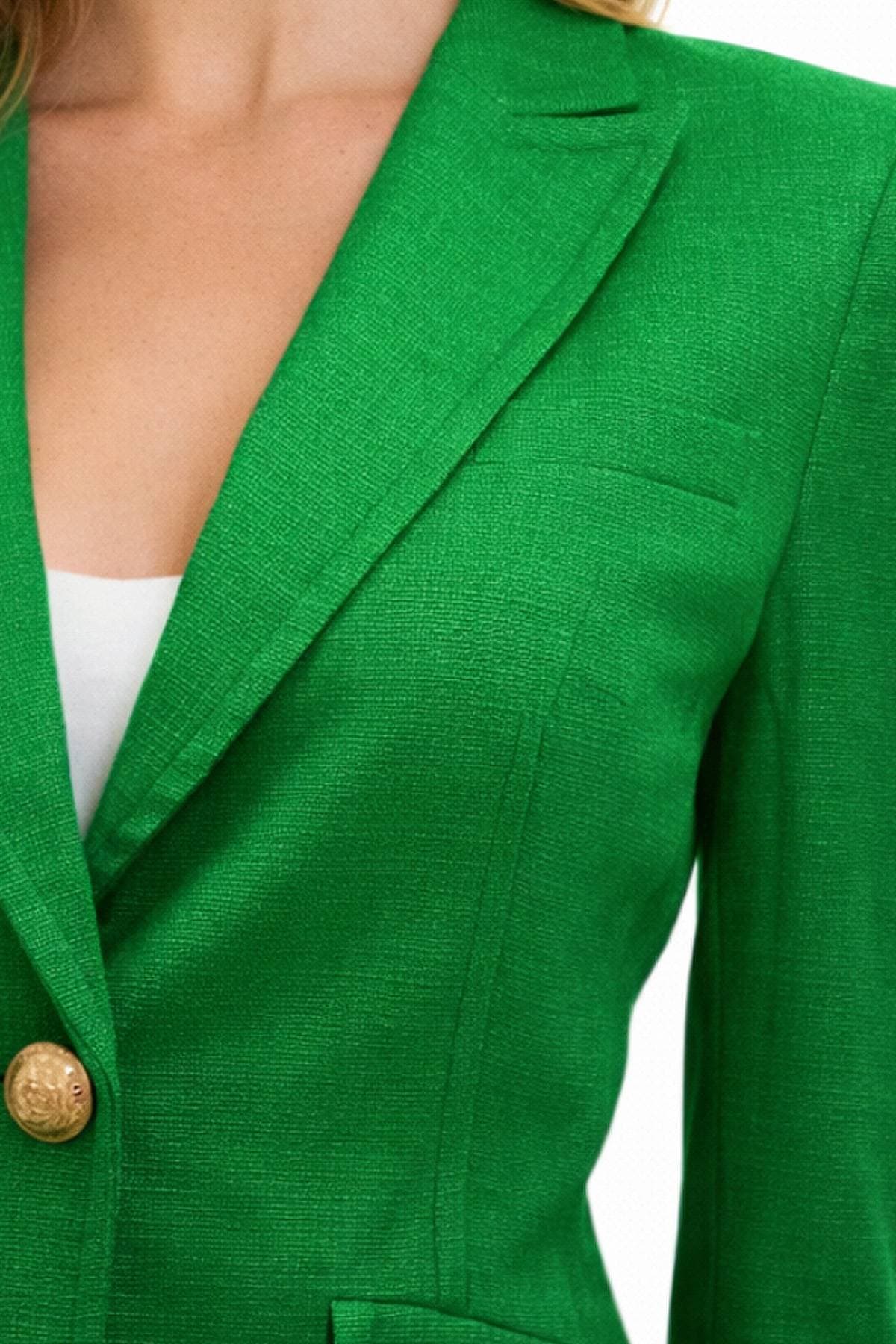 A close-up of a person wearing a green blazer with gold buttons.