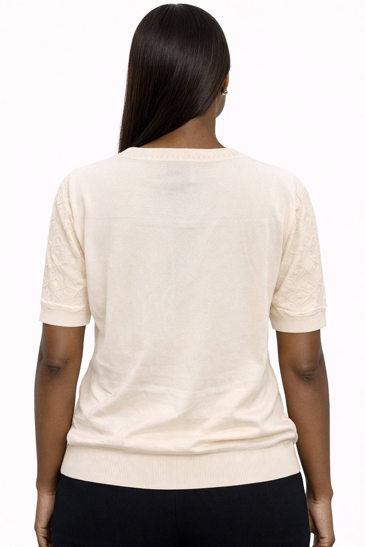 A person with long hair is wearing a light-colored short-sleeve top, viewed from the back.