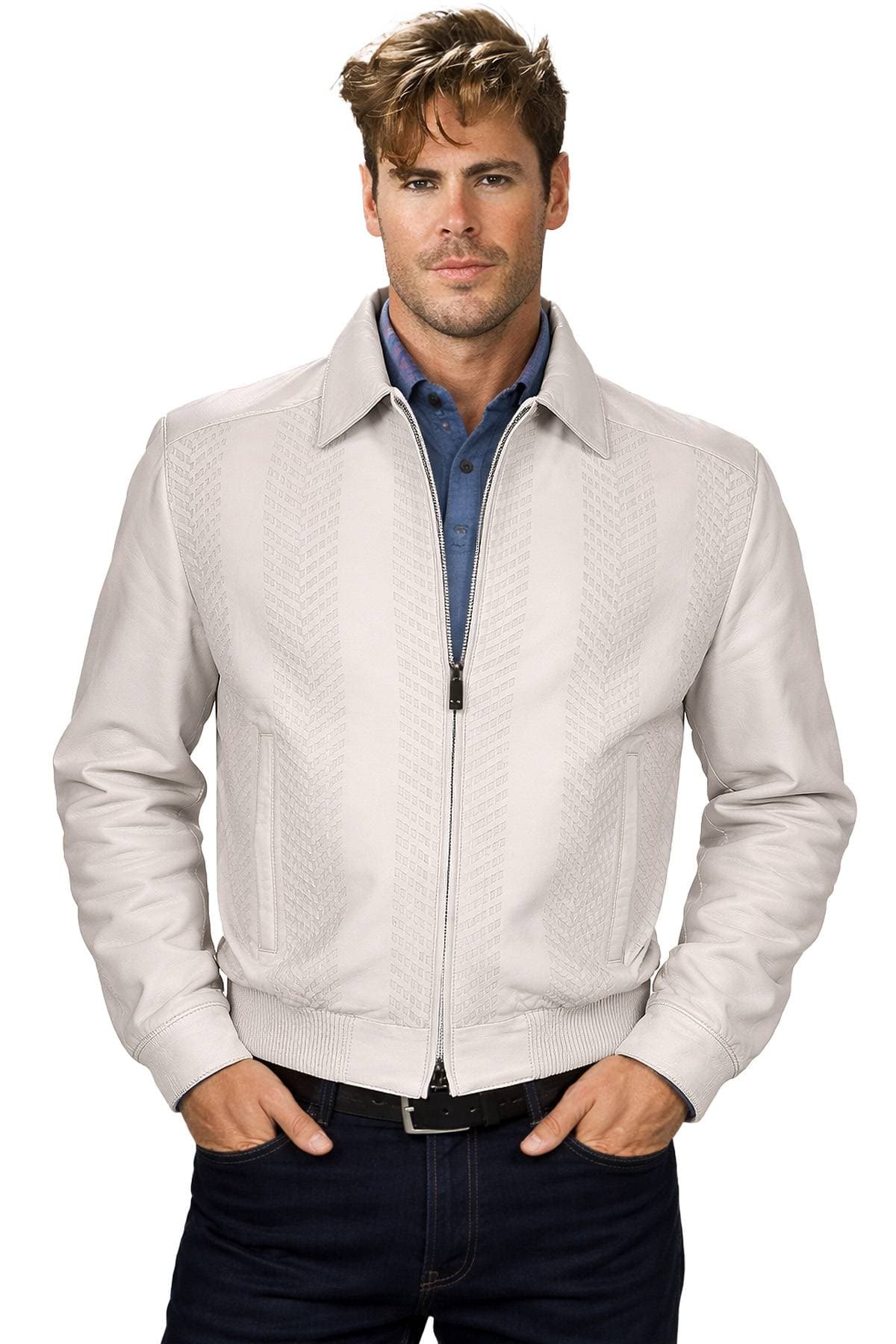 A man wearing a light-colored patterned jacket over a blue shirt with hands in his pockets.