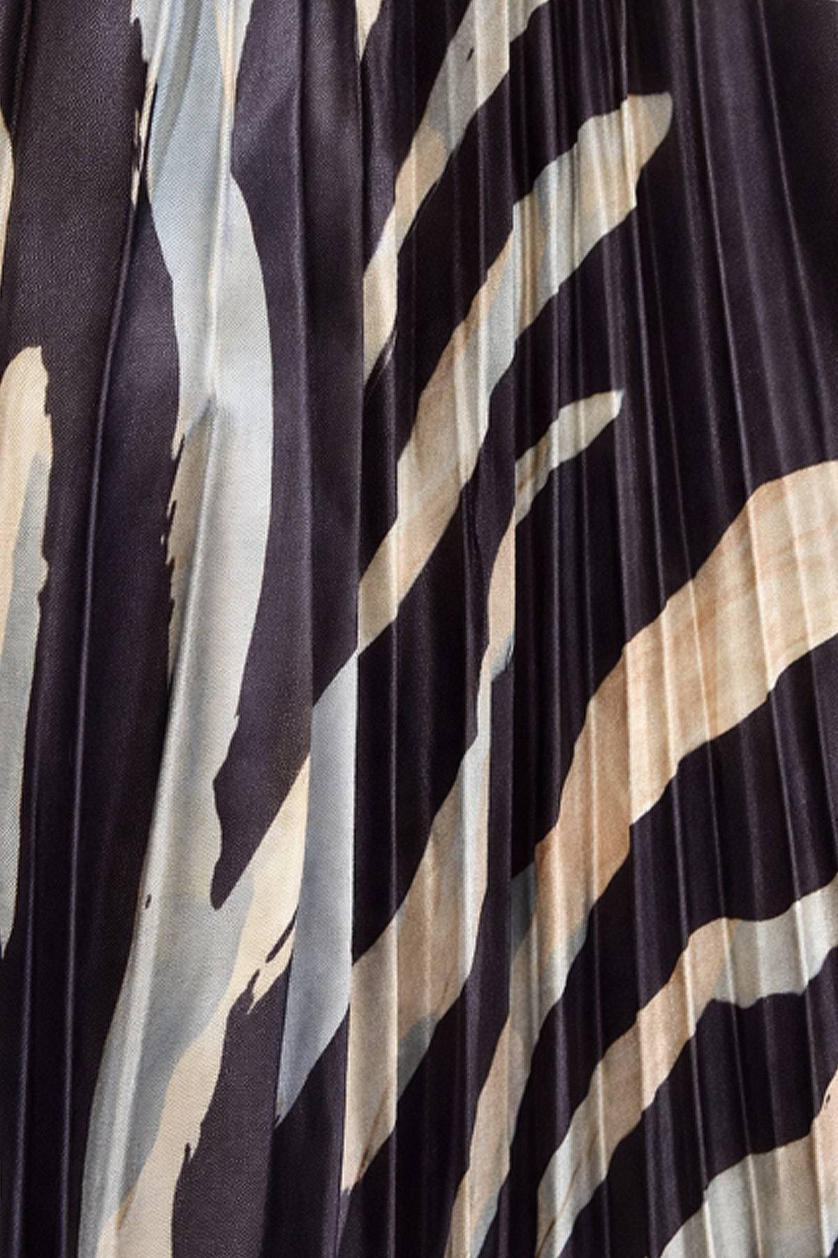 Close-up of pleated fabric with a bold, abstract pattern in dark and light colors.
