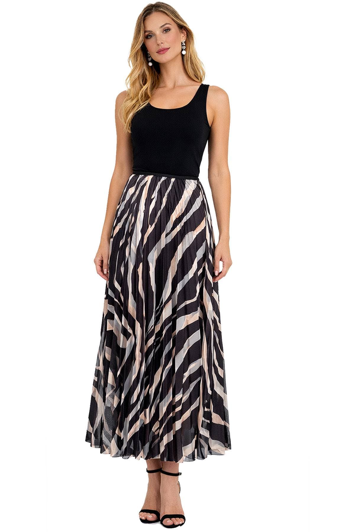A woman wearing a black sleeveless top and a long, patterned pleated skirt with black high-heeled sandals.
