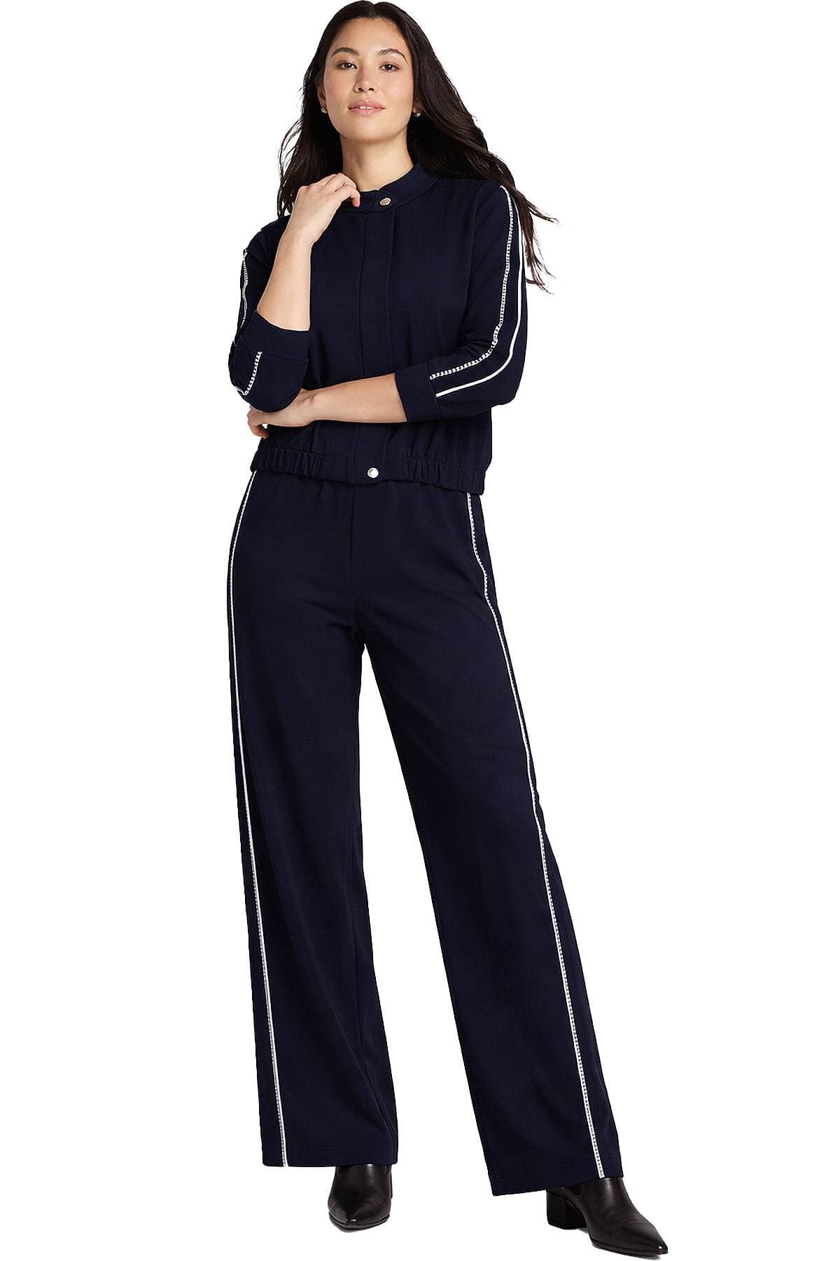 A woman wearing a dark blue matching set with white stripe details along the sleeves and pants.
