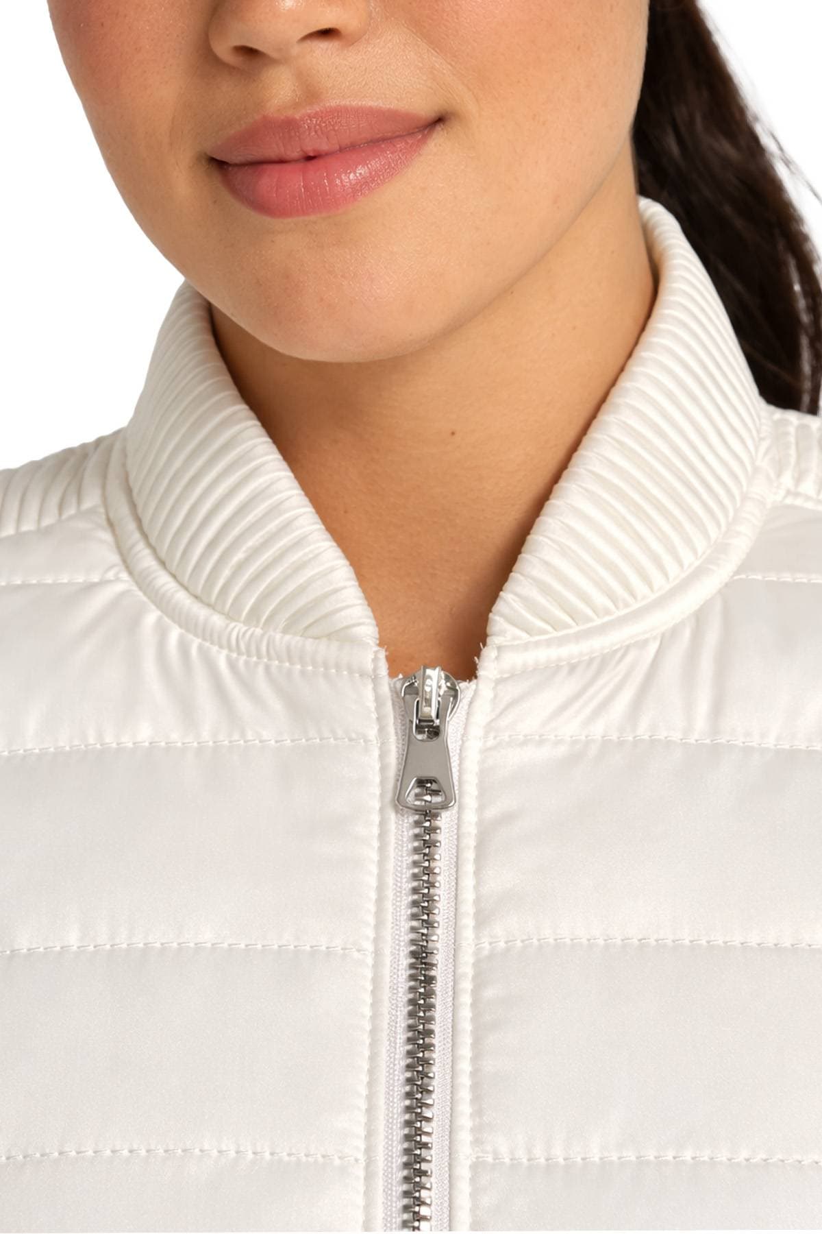 Close-up of a person wearing a white quilted jacket with a zip-up front.