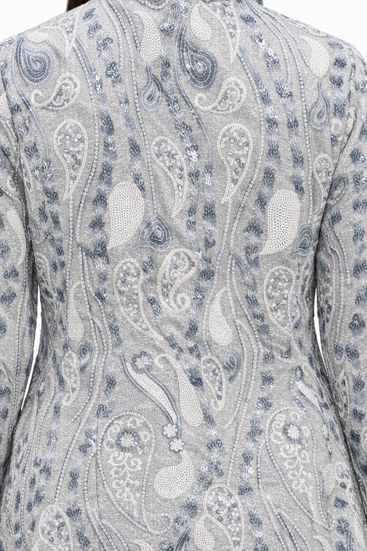 A close-up of a person's back wearing a jacket with a detailed paisley pattern in shades of blue and white.