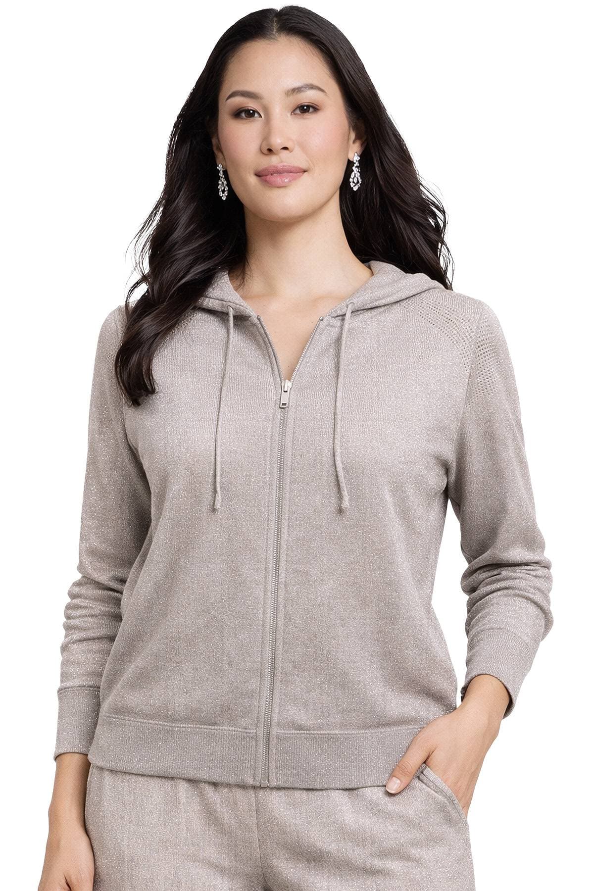 A woman is wearing a light grey zip-up hoodie with matching pants and silver earrings.