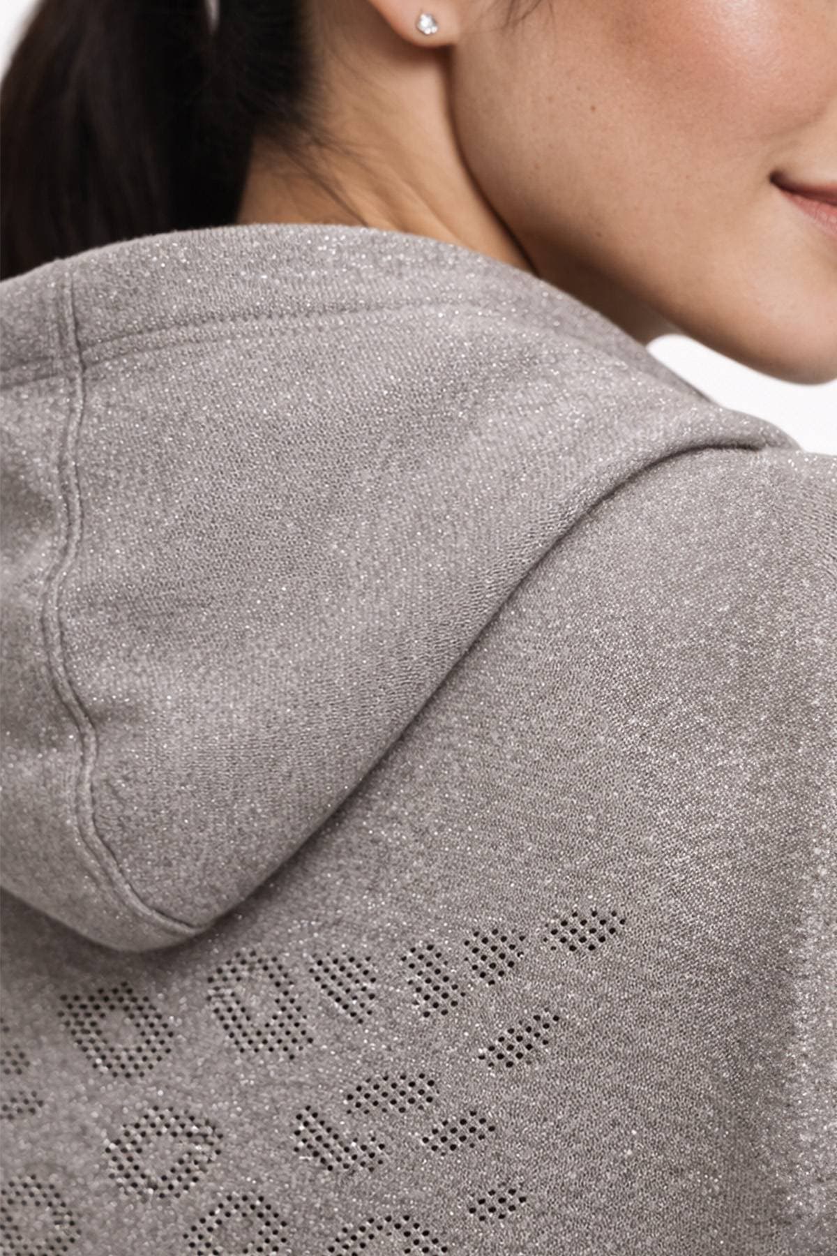 A person wearing a sparkly gray hoodie with a perforated pattern on the back.