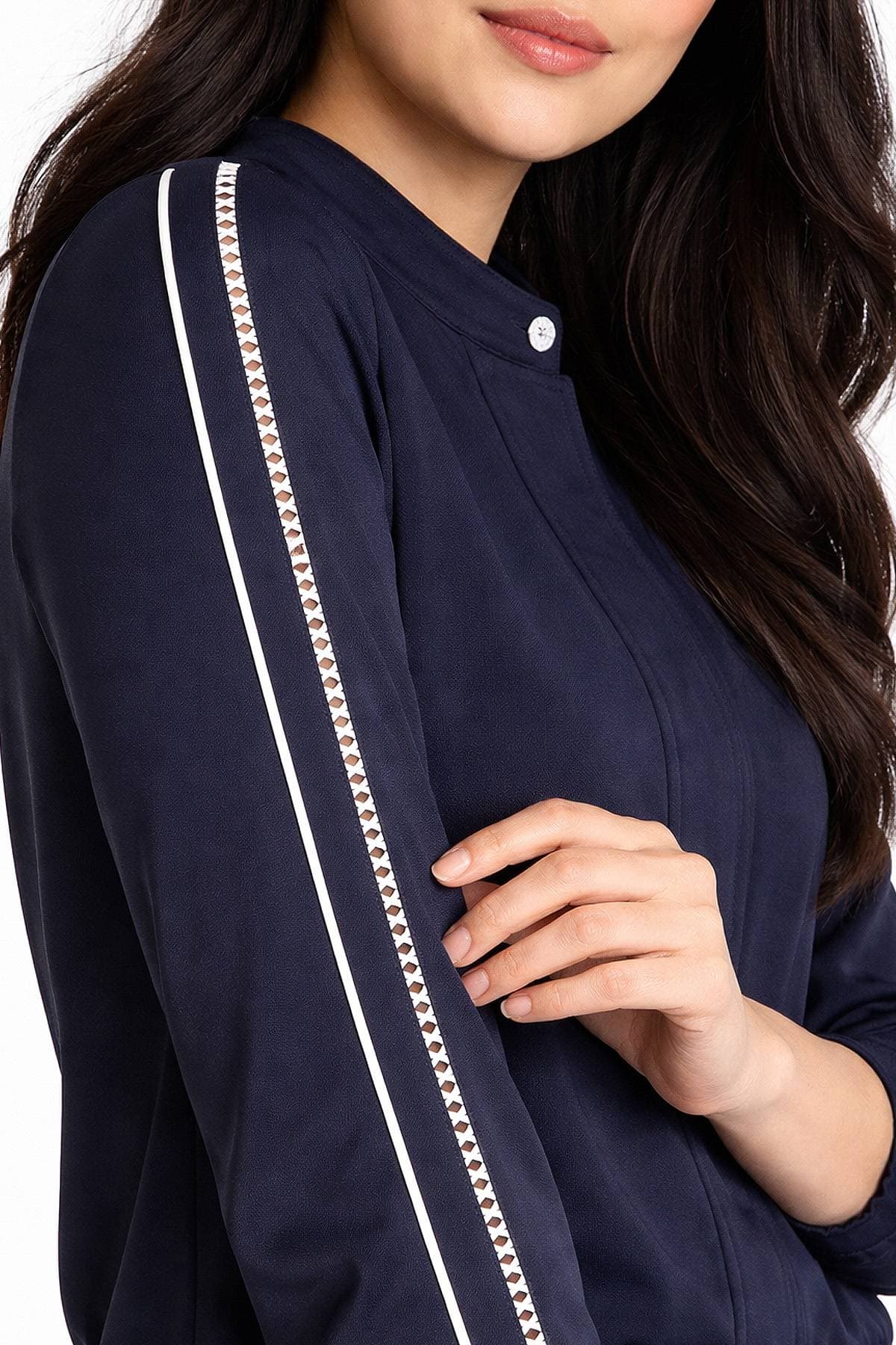 A person wearing a navy blue jacket with white striped detailing on the sleeves.