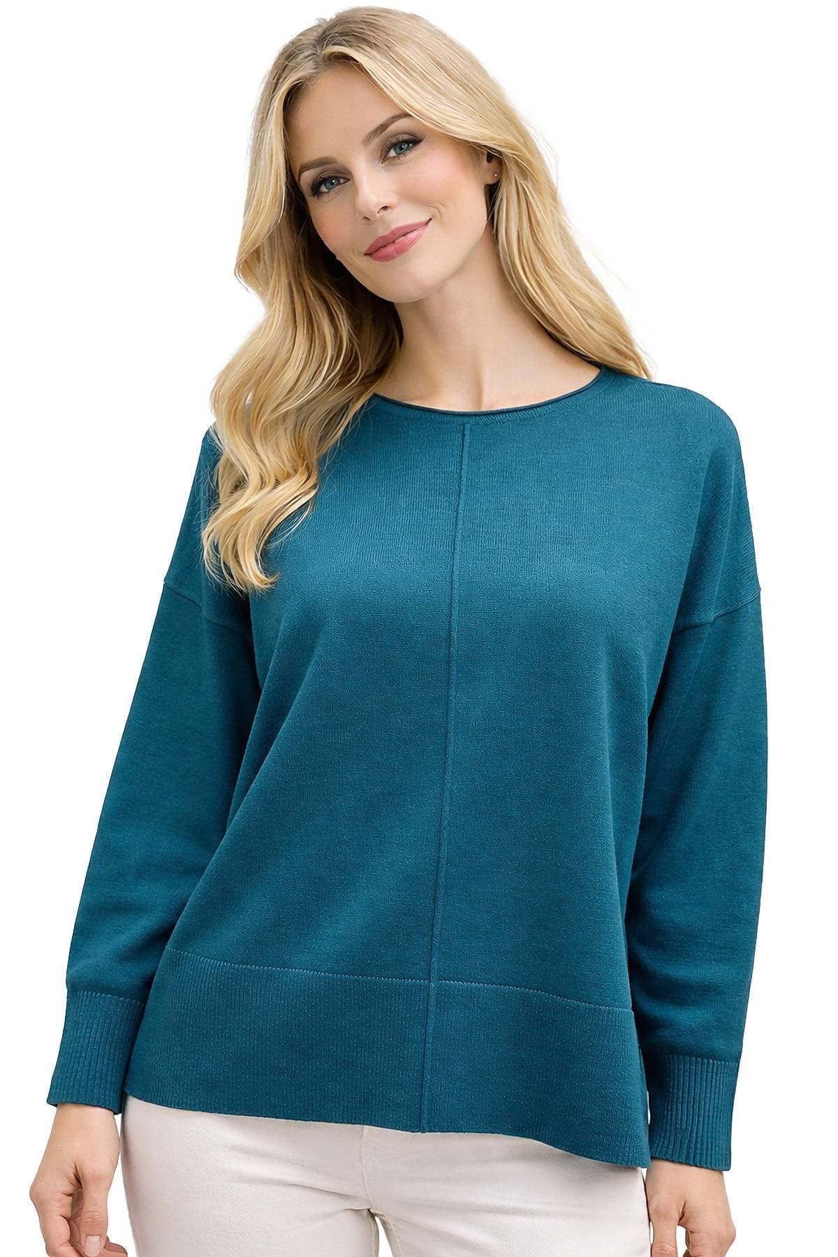 A person wearing a teal sweater with long sleeves and light-colored pants.