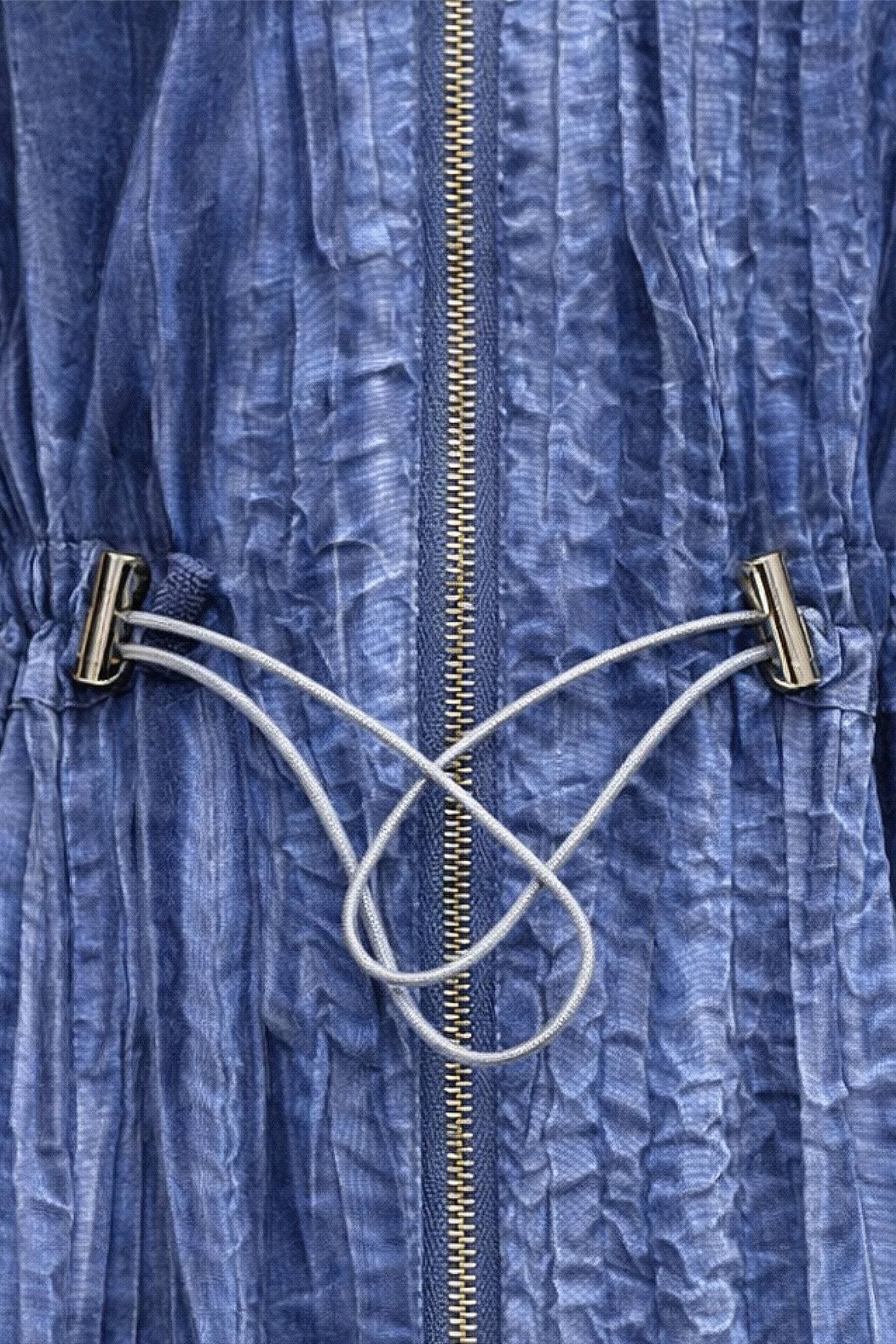 A close-up of a blue garment with a vertical zipper and drawstring closure.