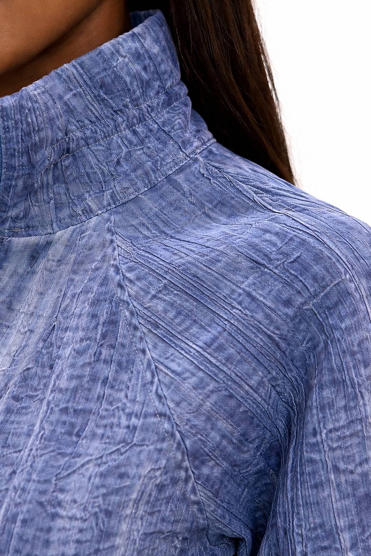 Close-up of a person wearing a textured blue high-collar garment.