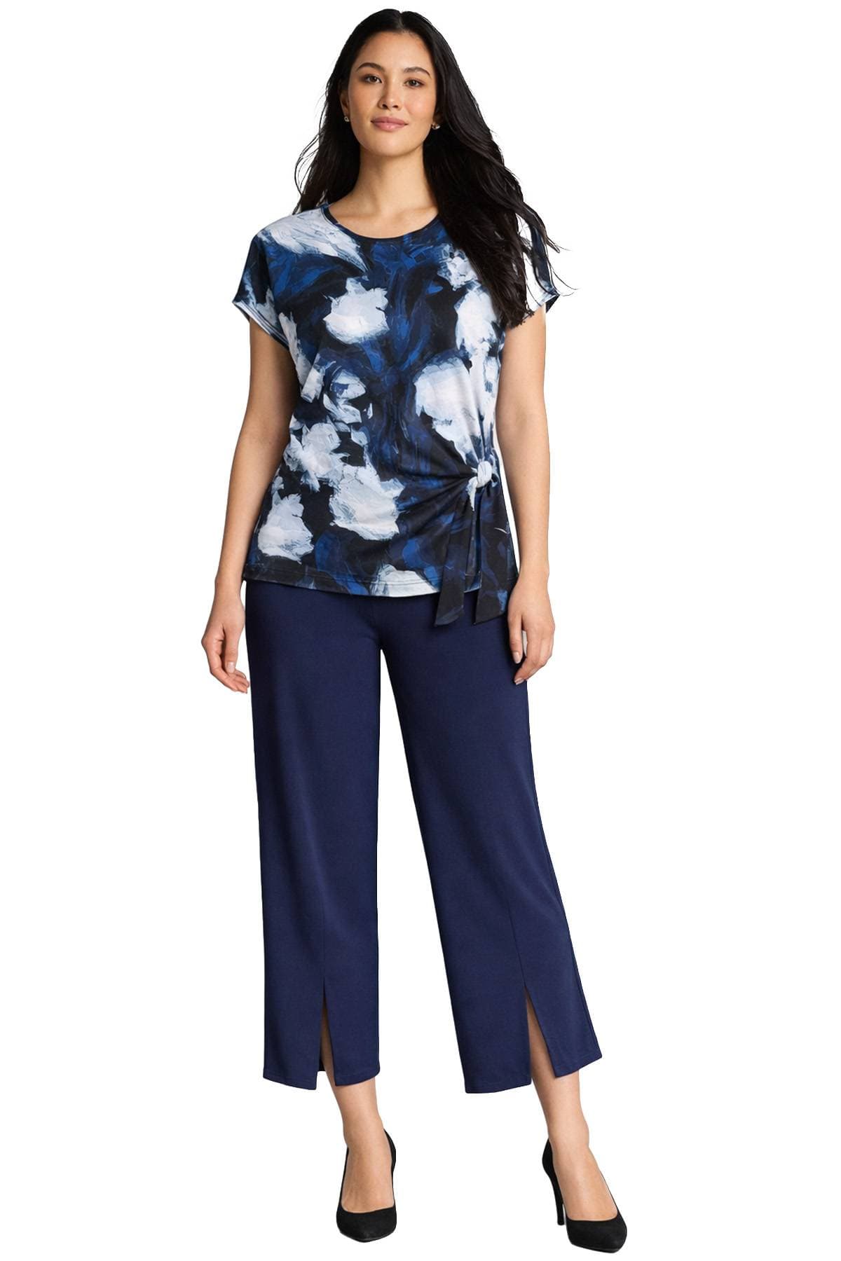 A woman wearing a blue and white patterned top with navy pants and black high heels.