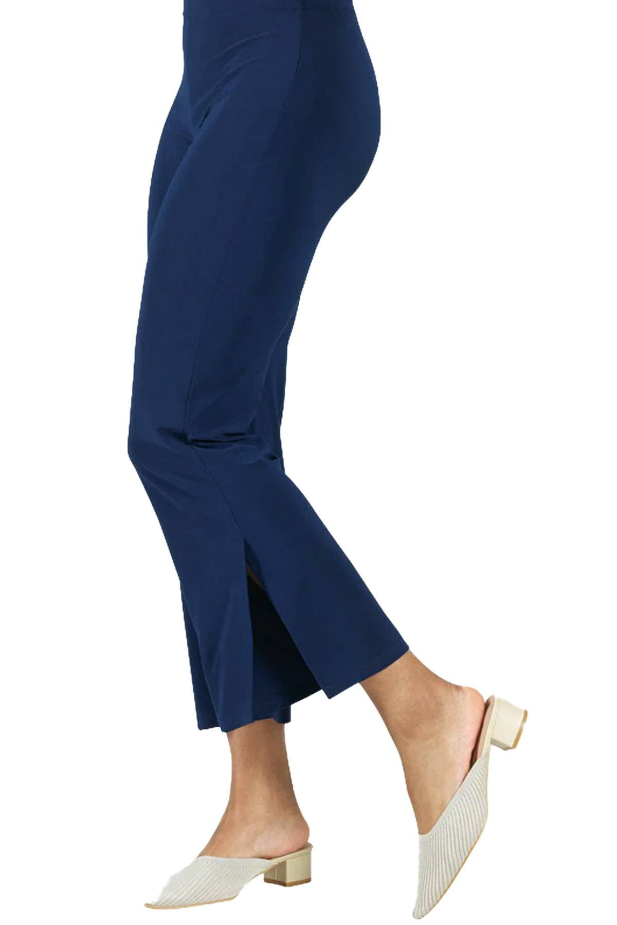 A person wearing navy blue cropped pants and beige heeled mules.