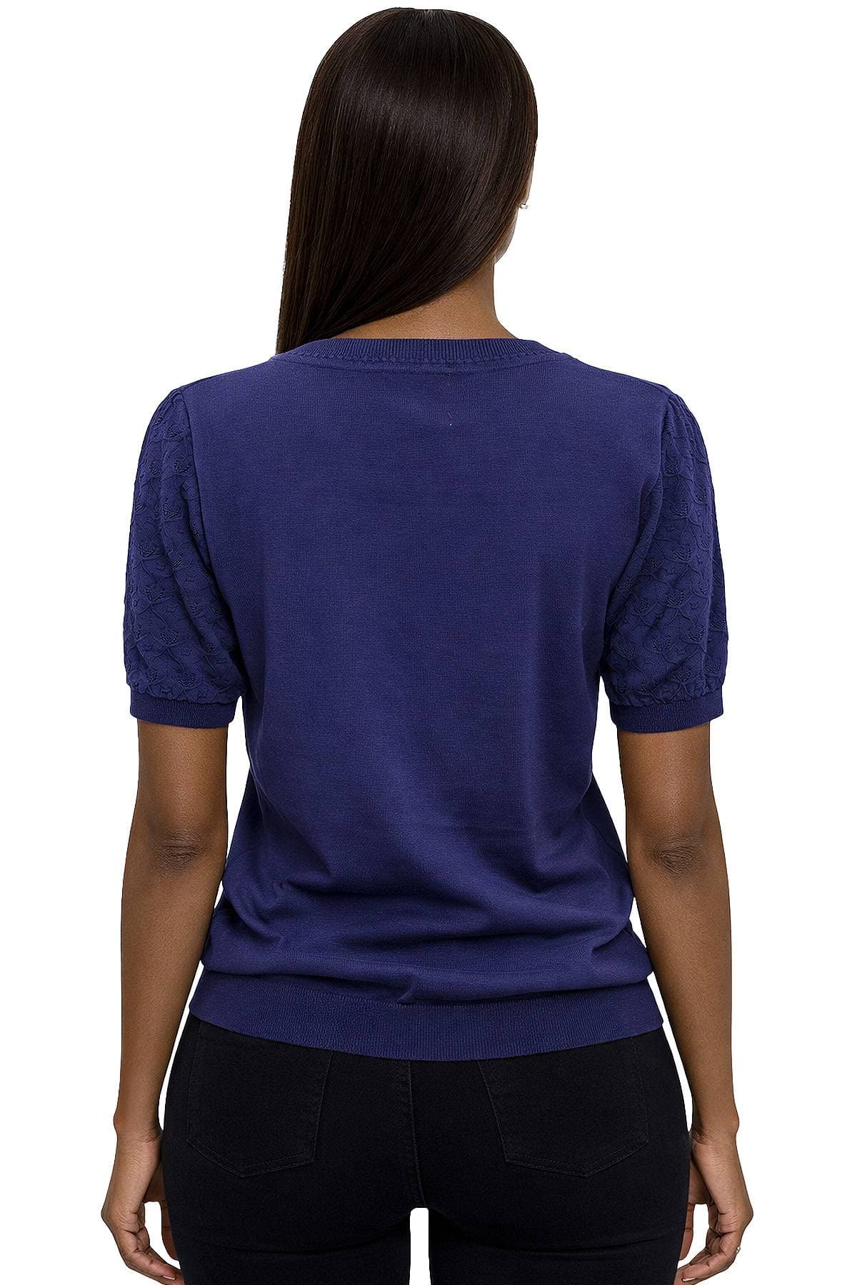 A person wearing a blue short-sleeved sweater and black pants is shown from the back.