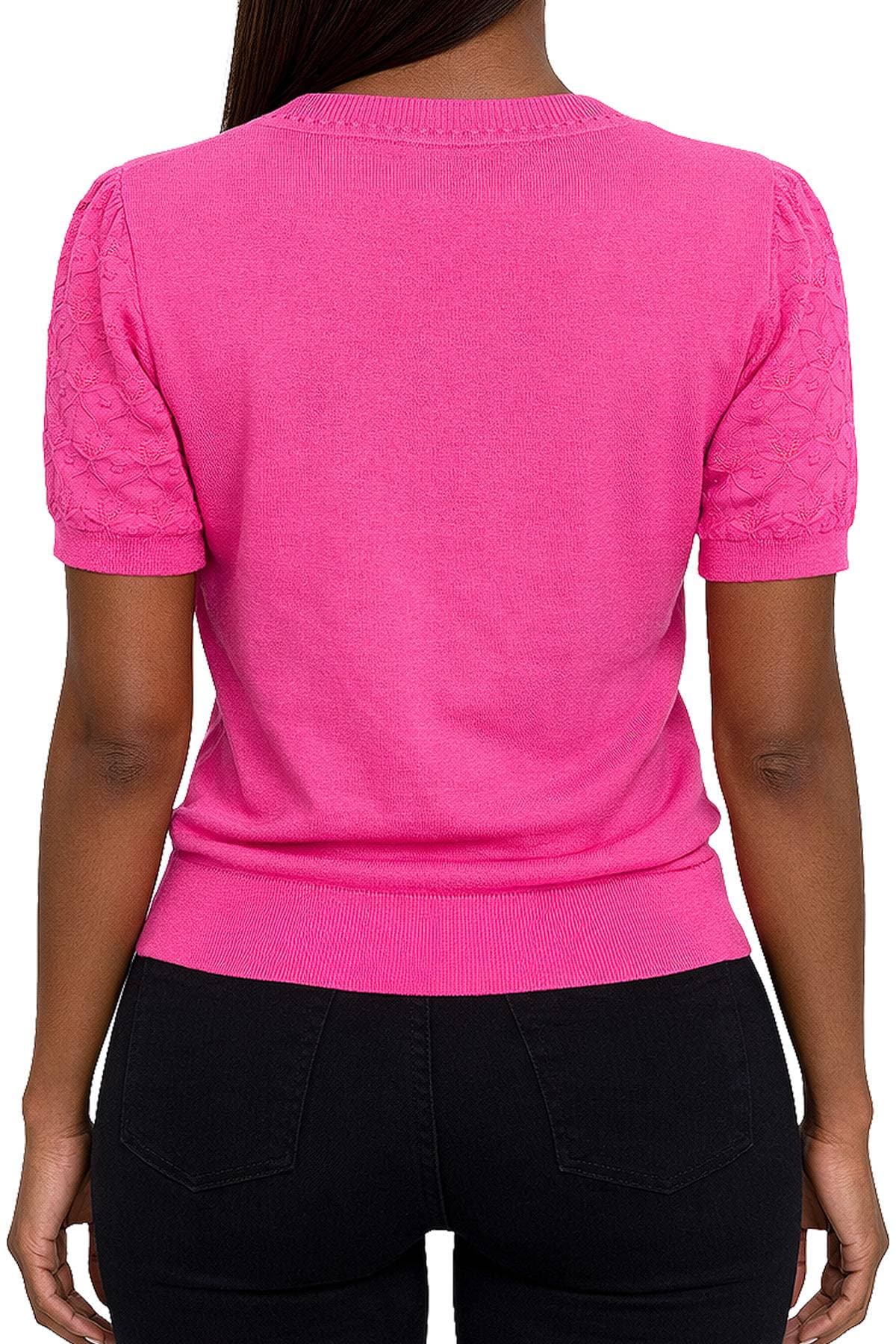 A person wearing a bright pink short-sleeved top with textured sleeves and black pants is shown from the back.