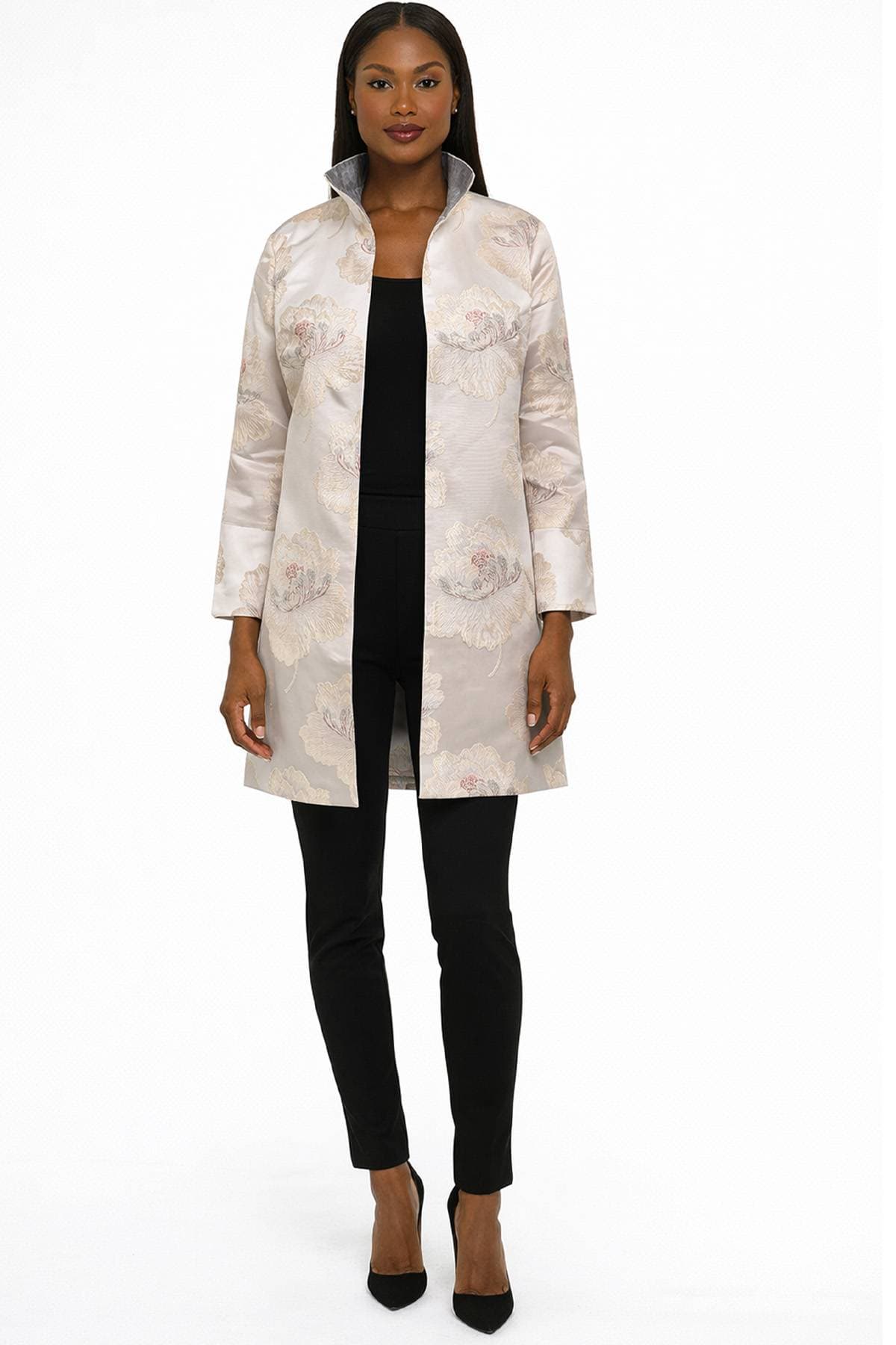 A woman is wearing a light floral patterned coat over a black outfit with black heels.