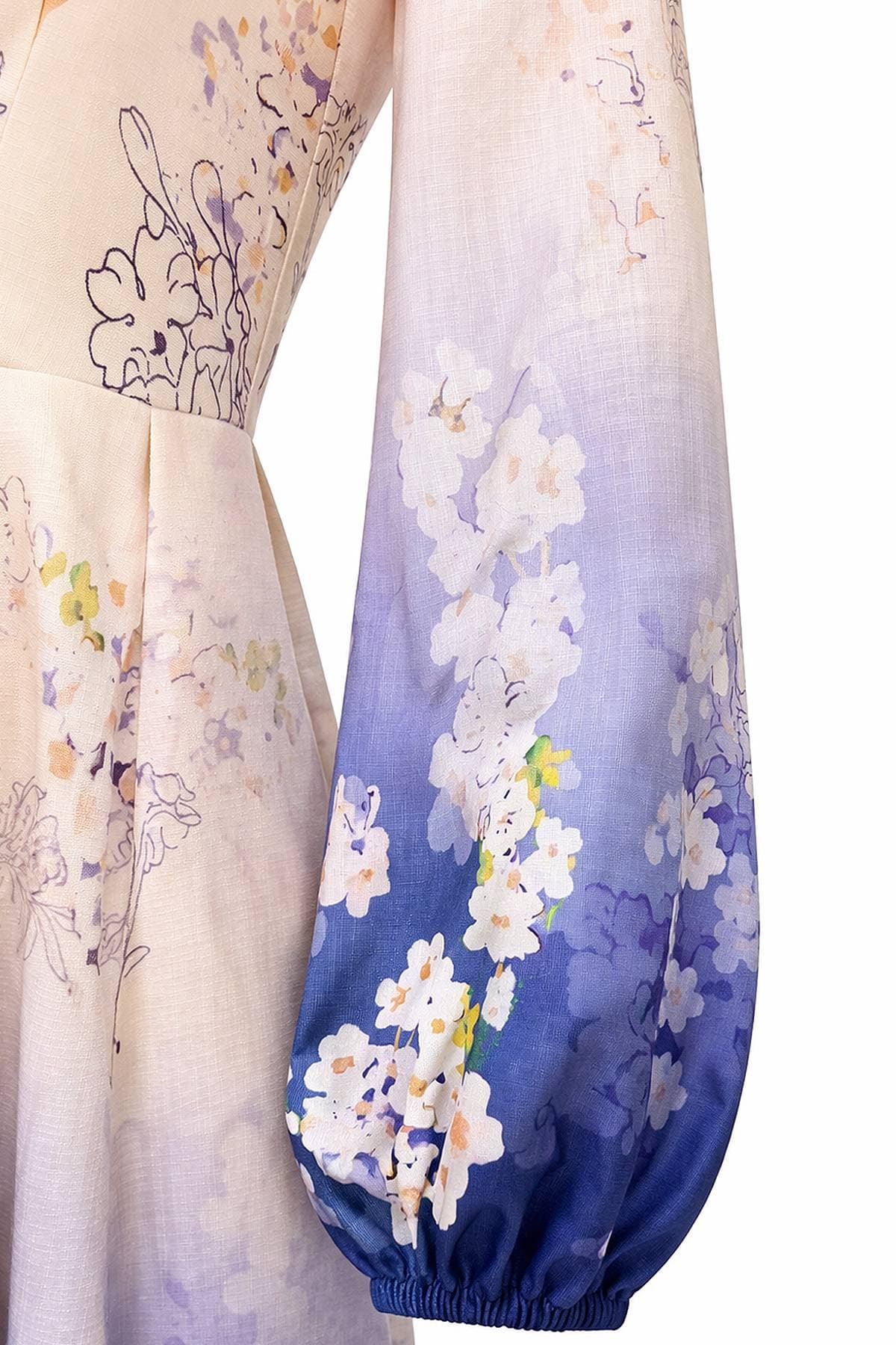 A close-up of a long-sleeved dress featuring a soft floral pattern transitioning from beige to purple with elastic cuffs.