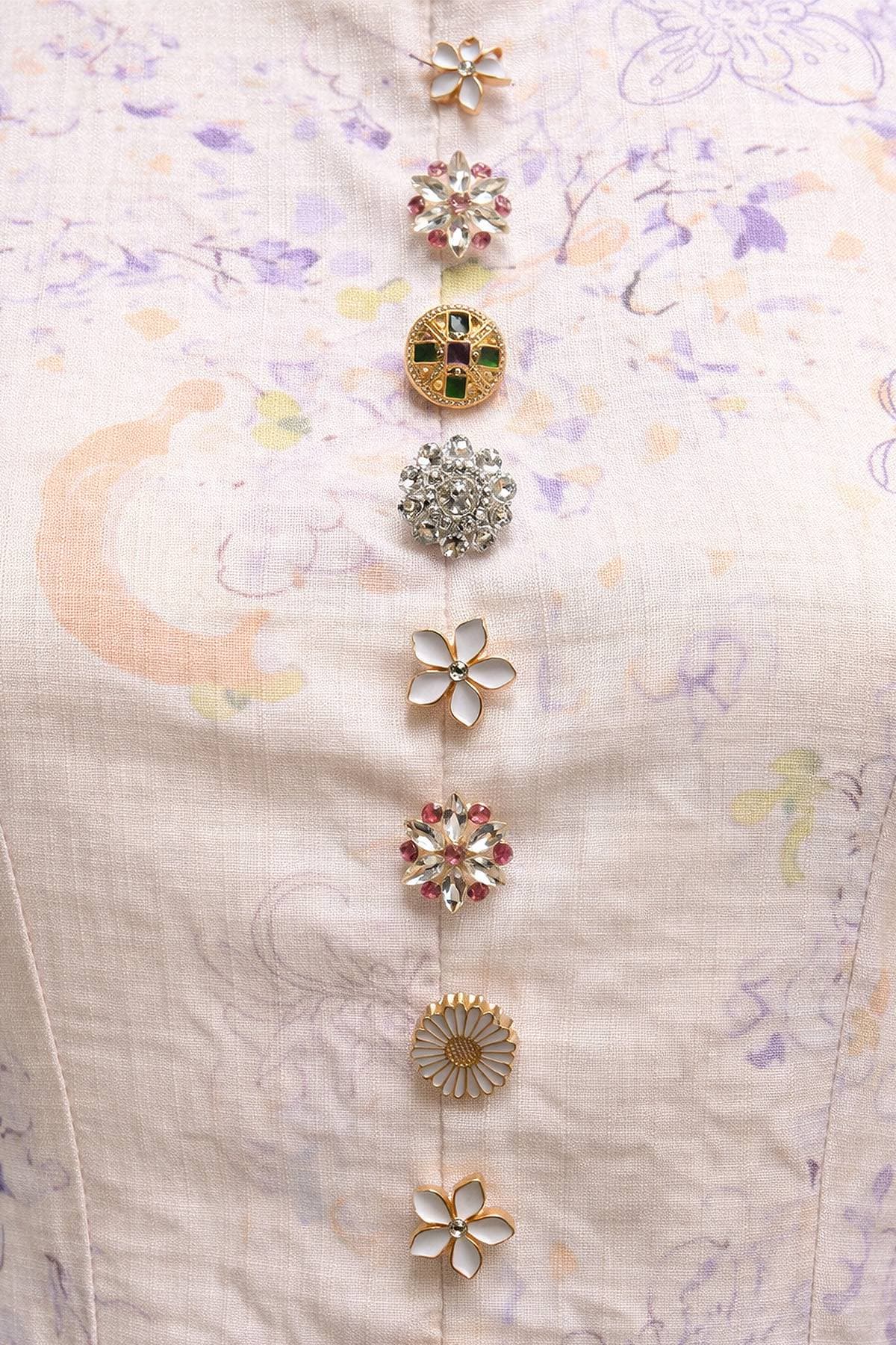 A series of seven decorative buttons in various floral and geometric designs are arranged vertically on a light-colored fabric.