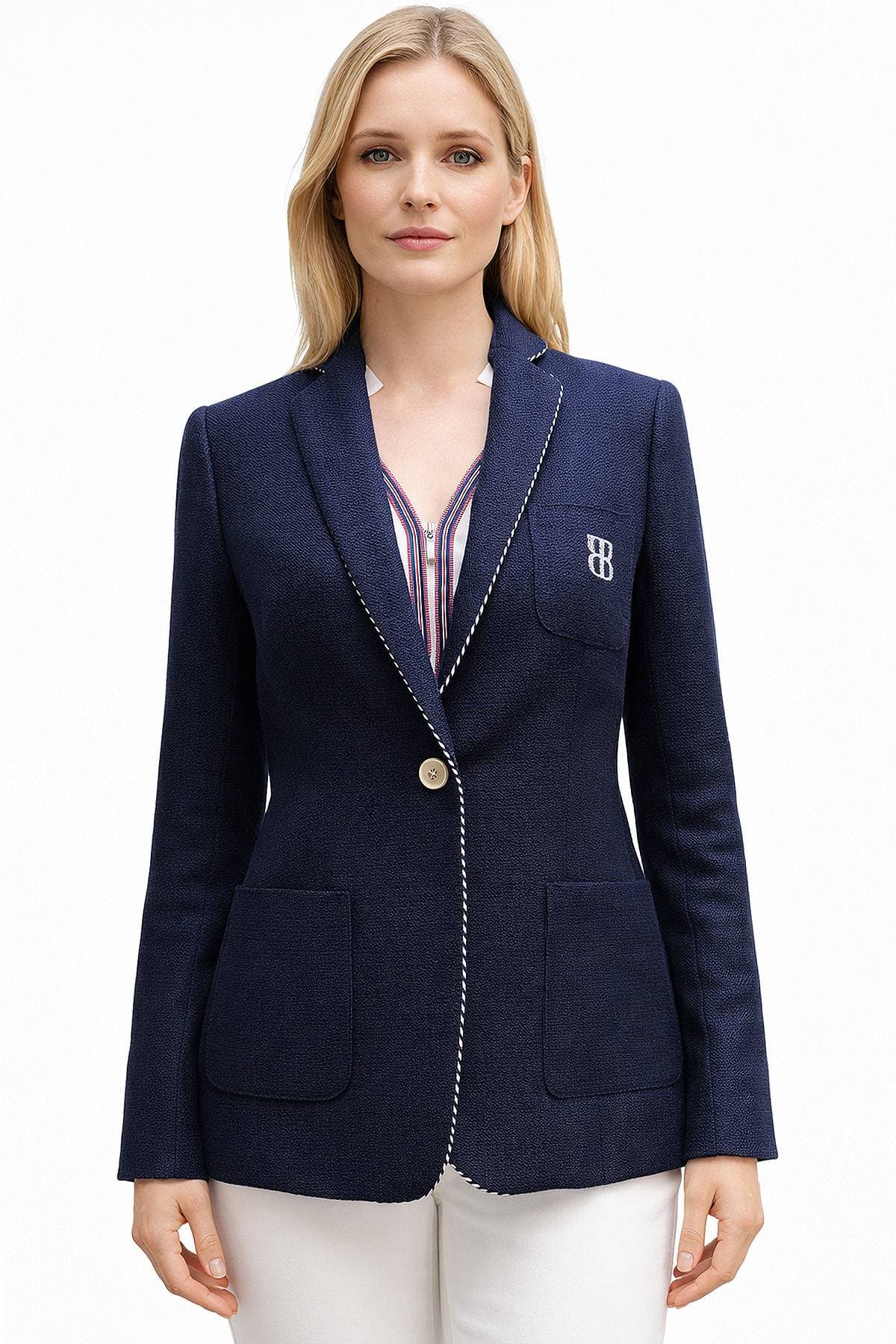 A person wearing a navy blazer with a monogrammed pocket and white pants.